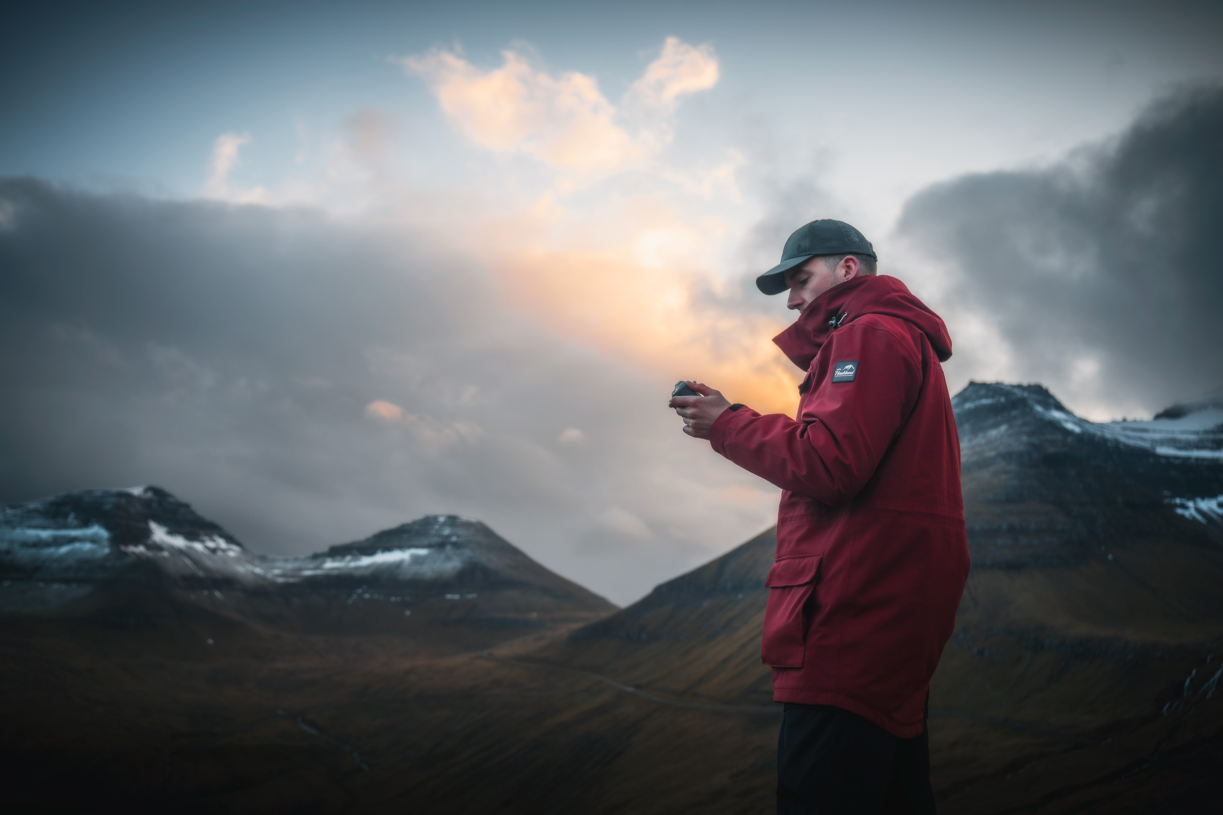 Reisender prüft sein Smartphone, während Sonnenlicht über den Bergen hervorbricht