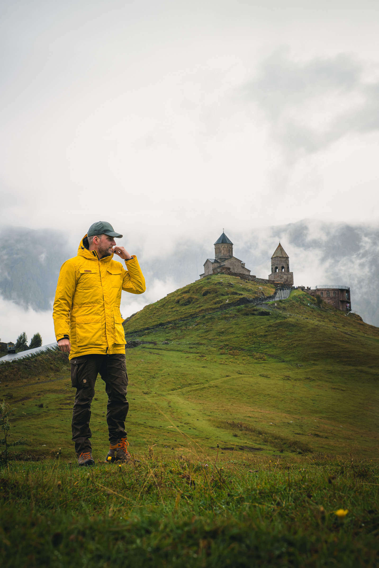 Reisender in gelber Jacke mit Blick auf die Gergetier Dreifaltigkeitskirche