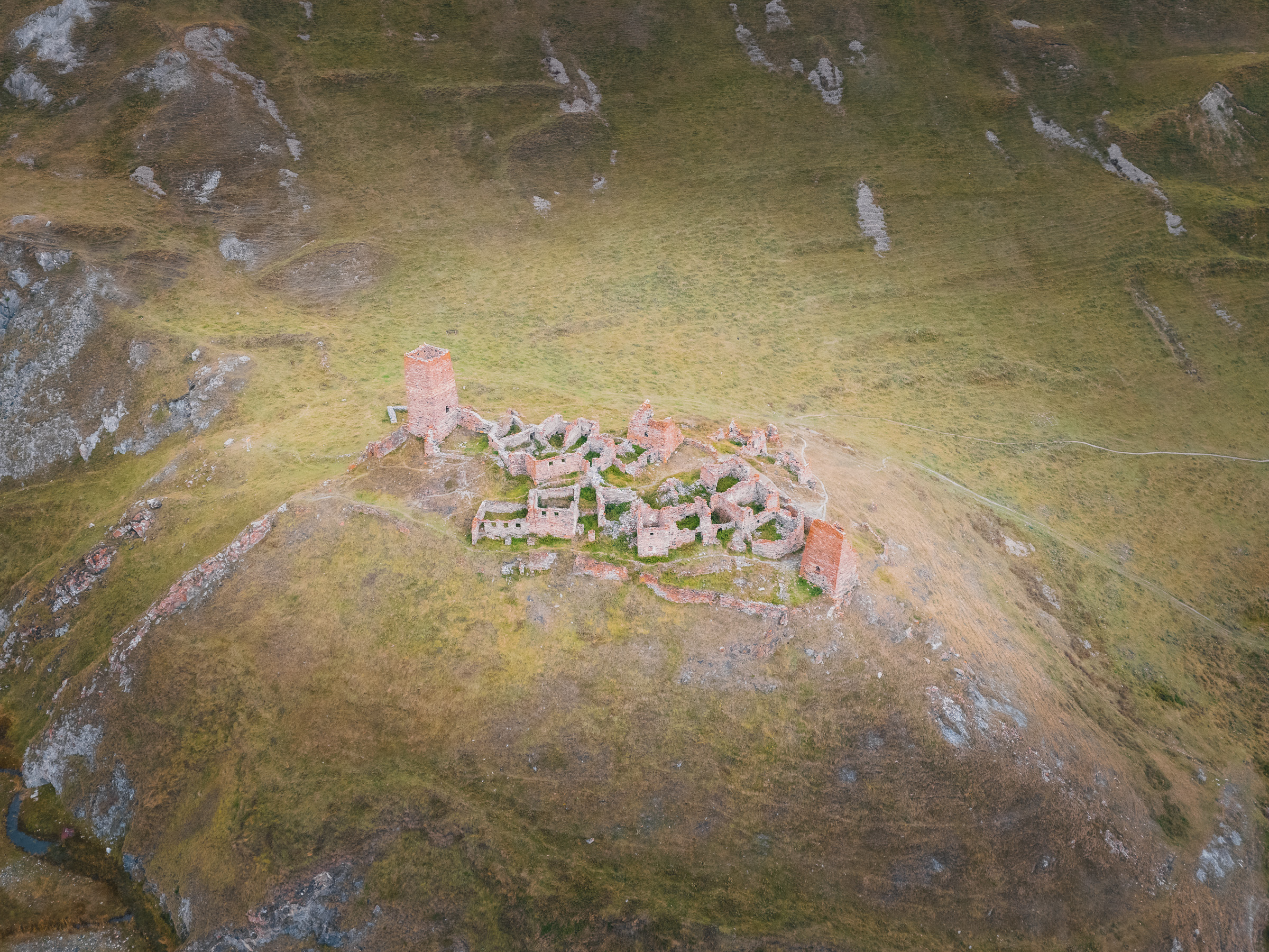 Luftaufnahme von Steinruinen auf einem grasbewachsenen Berghang