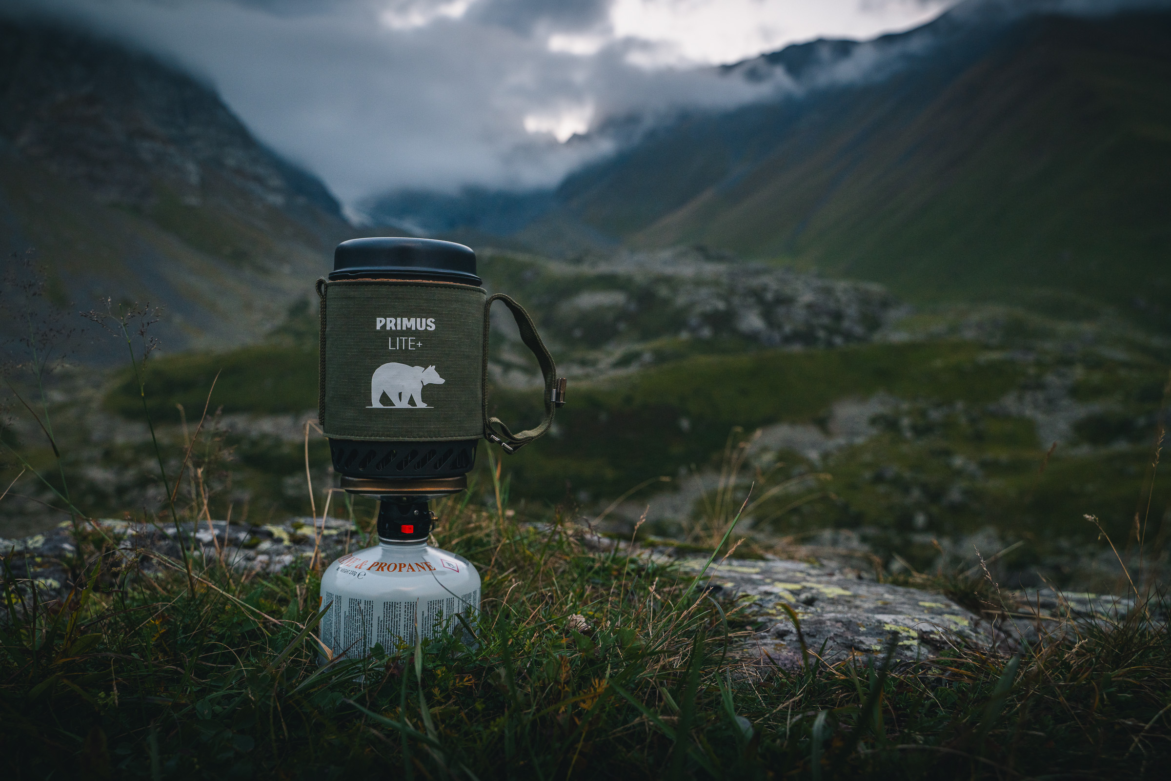 Campingkocher vor einem wolkenverhangenen alpinen Tal