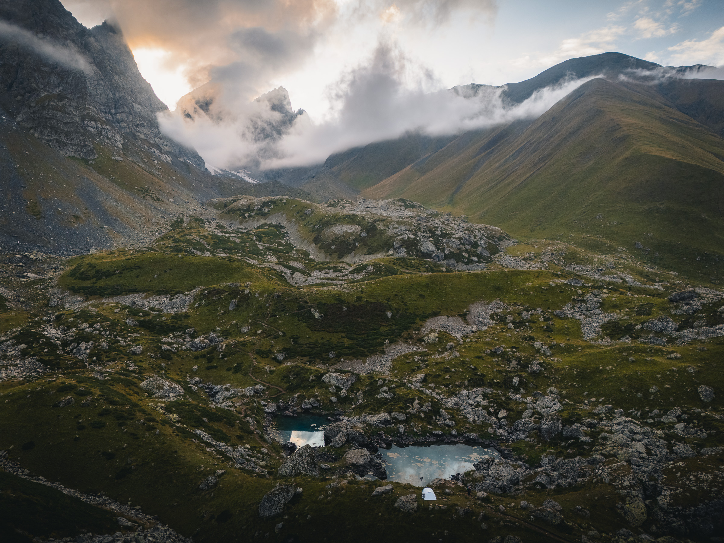 Felsiger alpiner Bergkessel mit kleinen Seen unter ziehenden Wolken