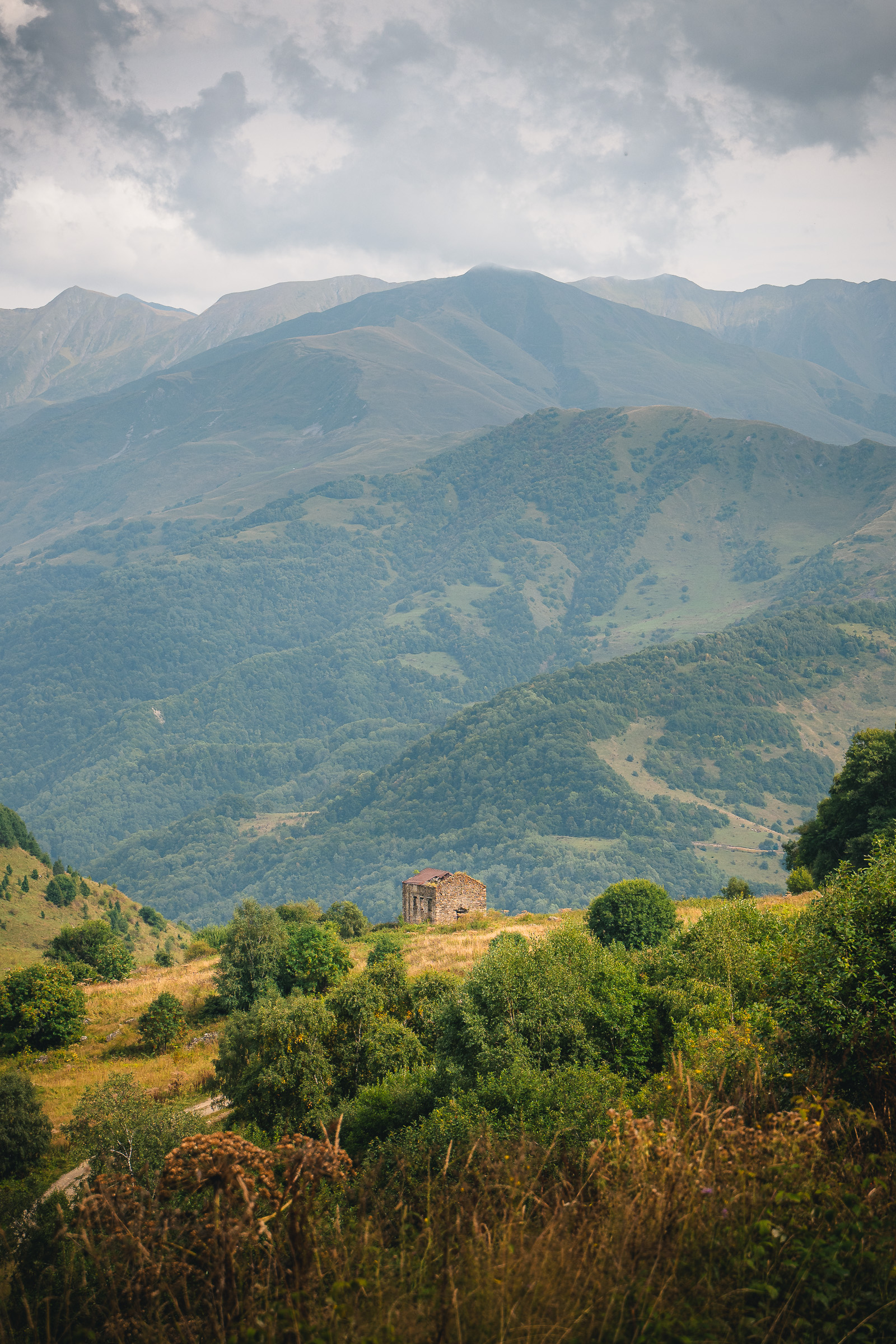 Entfernter Steinturm und Dorf auf der anderen Seite eines grünen Gebirgstals