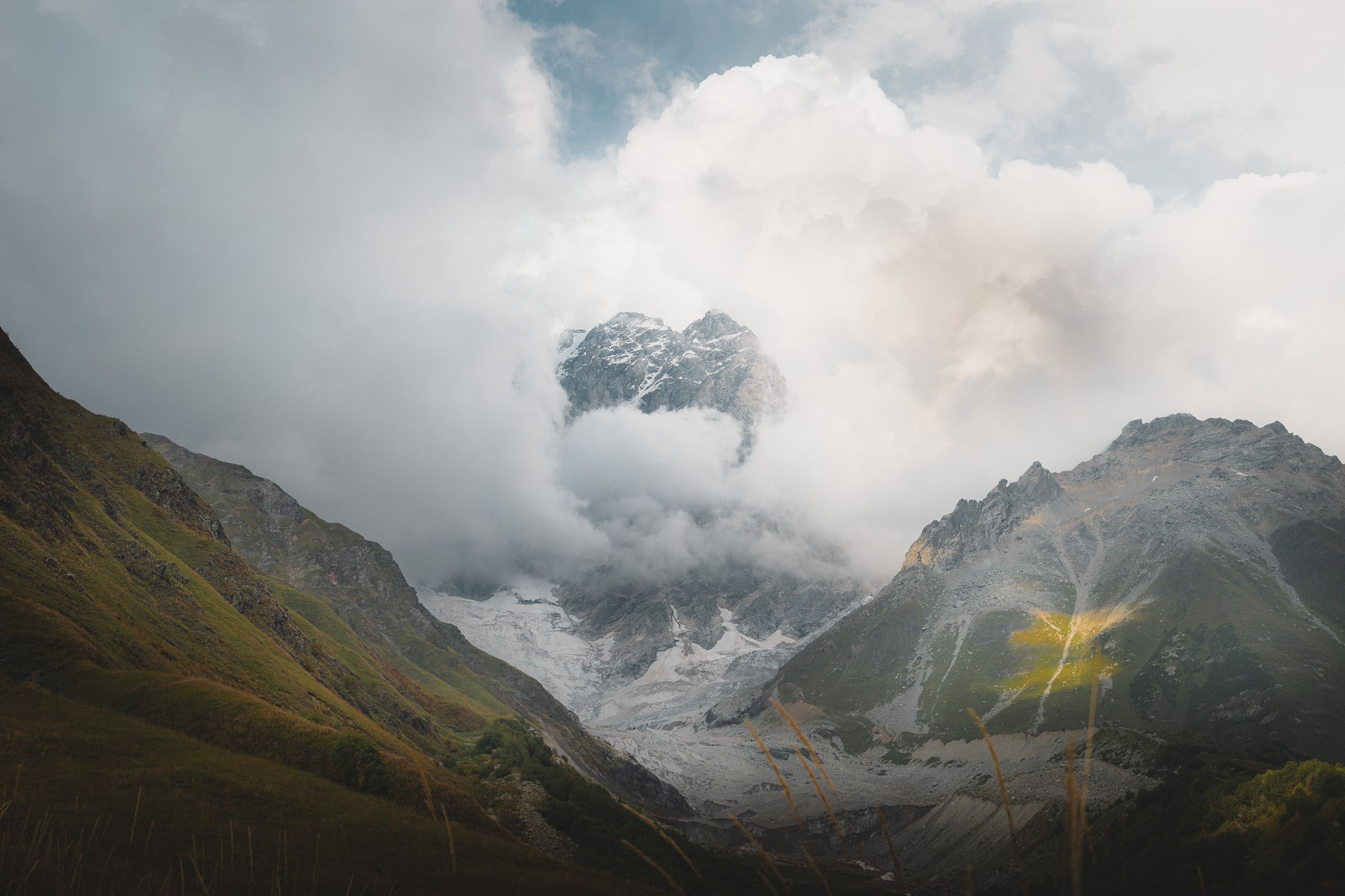 Schneebedeckter Berggipfel taucht aus dichten Wolken auf