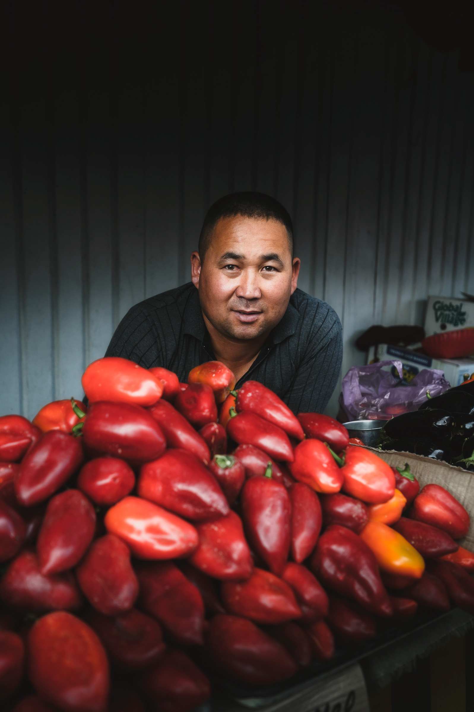 Market vendor surrounded by bright red peppers