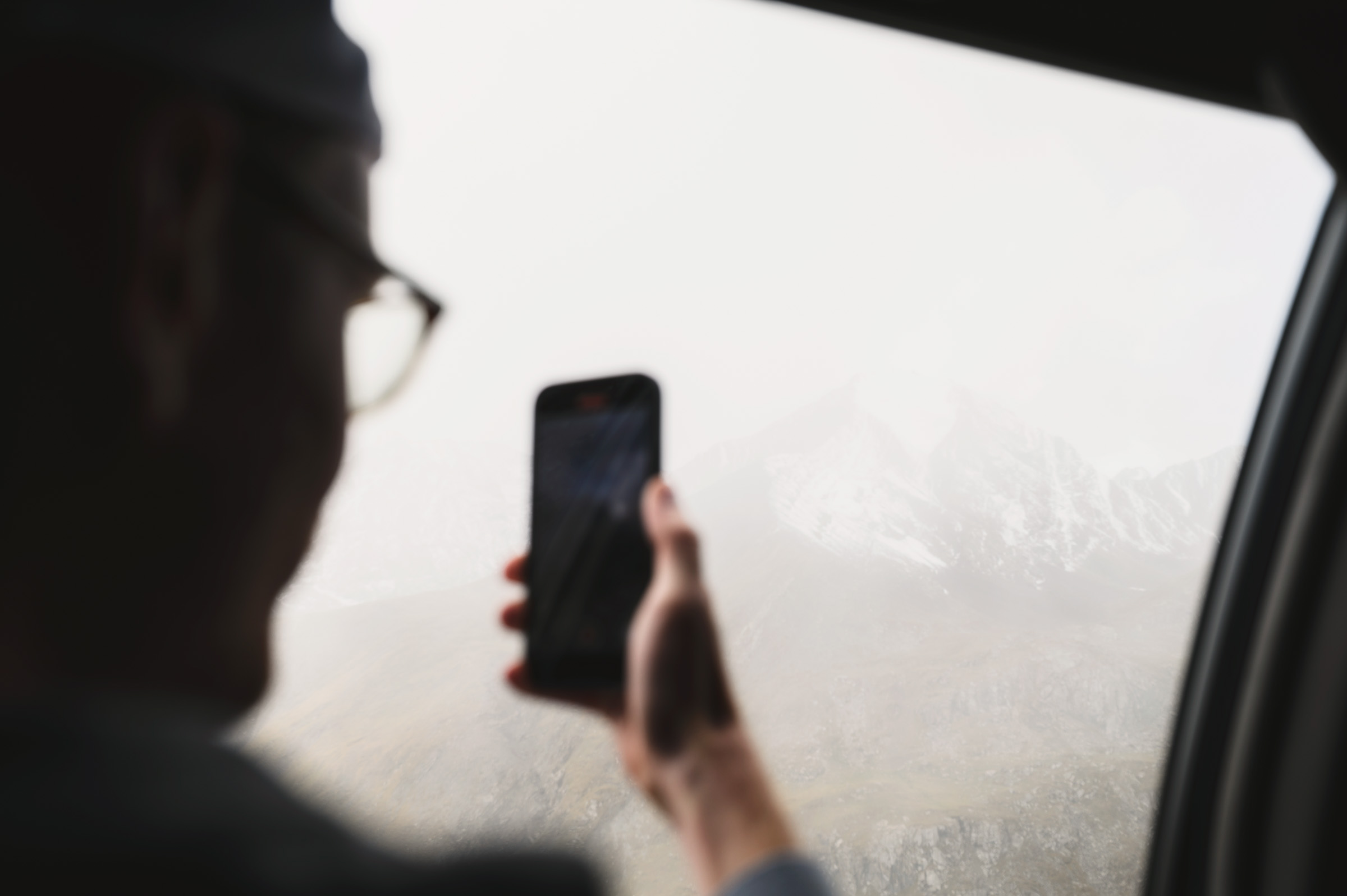 Passenger holding a phone beside a misty car window