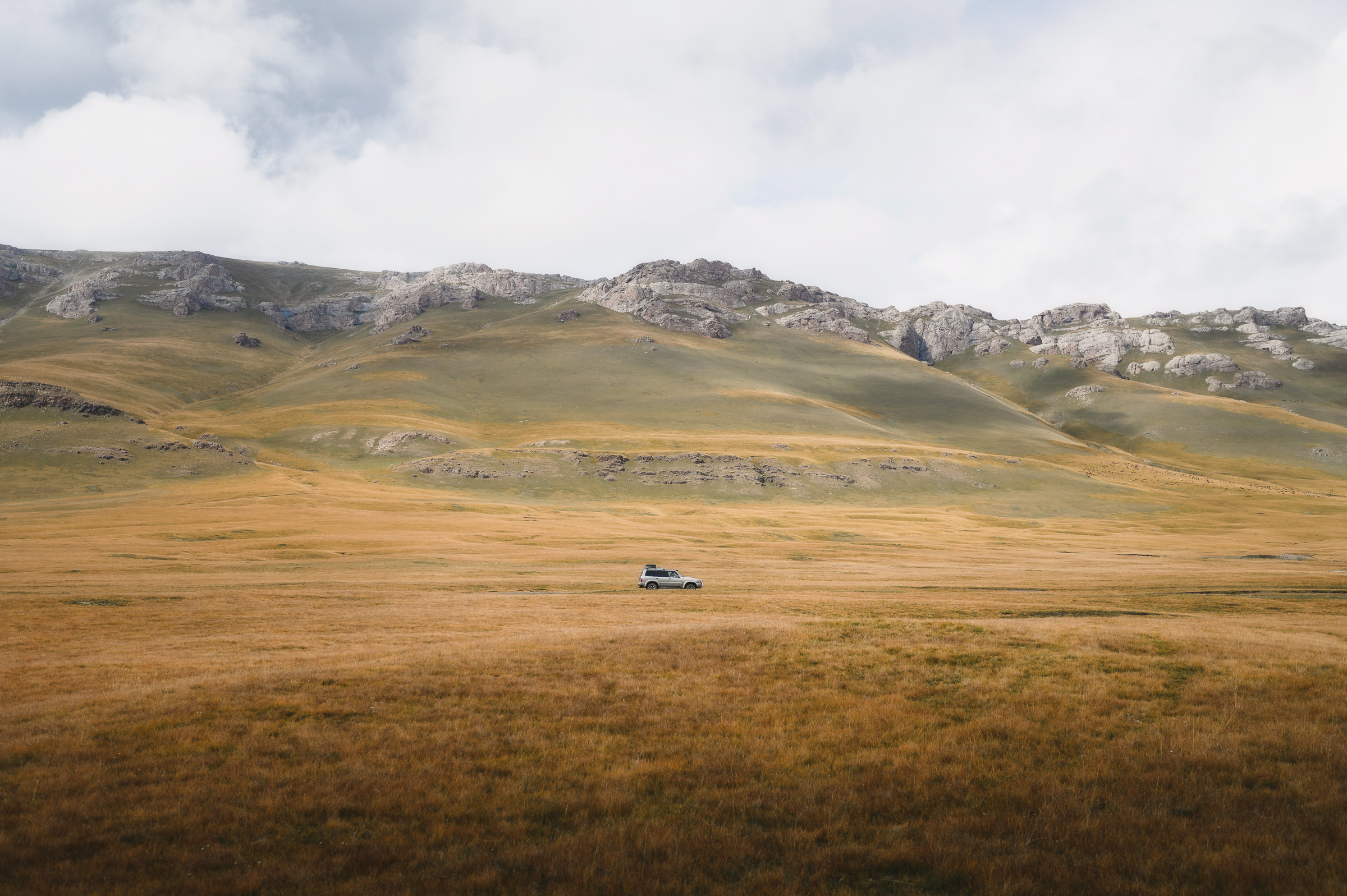 Off-road vehicle crossing a broad high-altitude plain