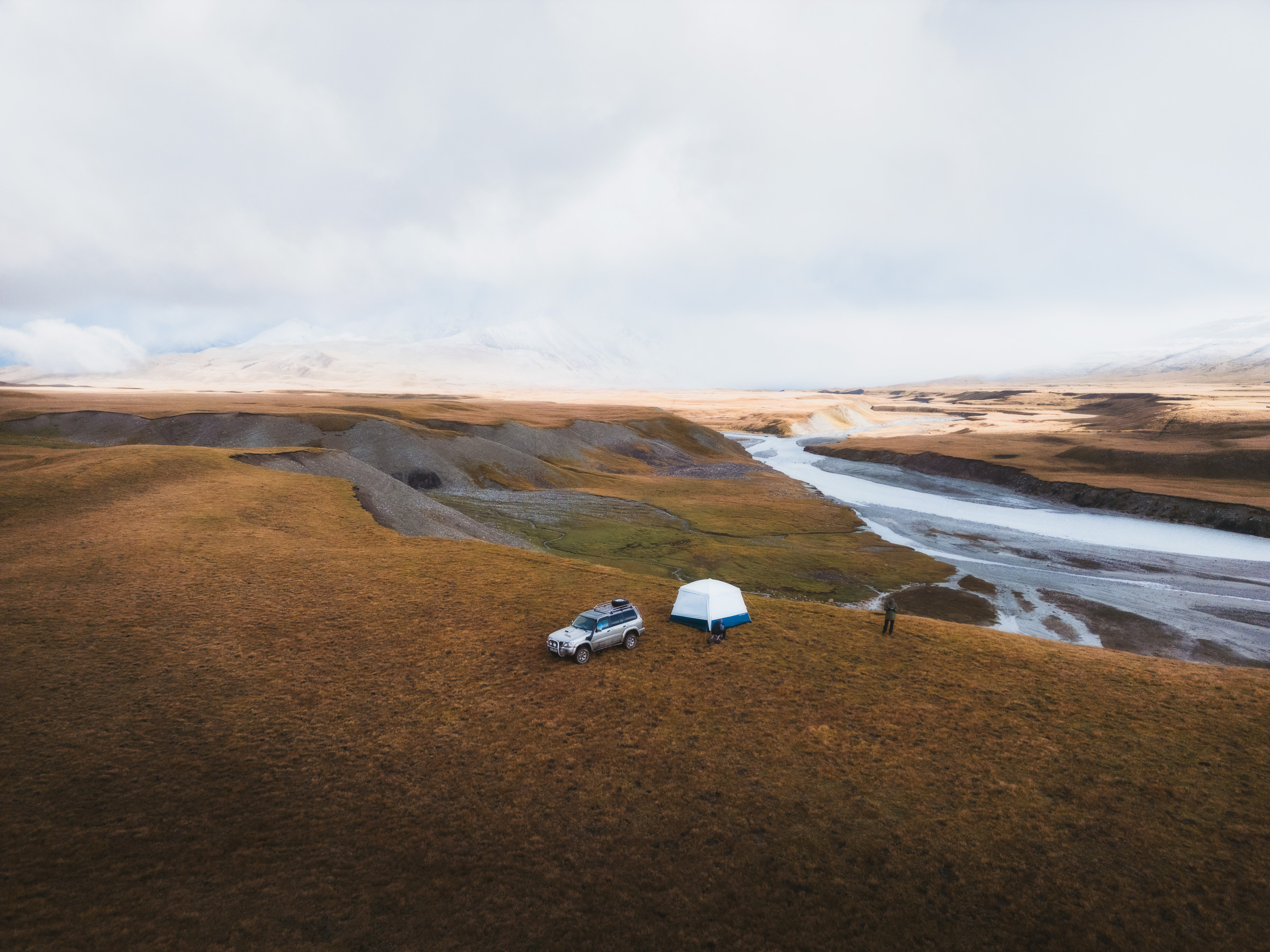 Tents beside a braided river on a remote plateau