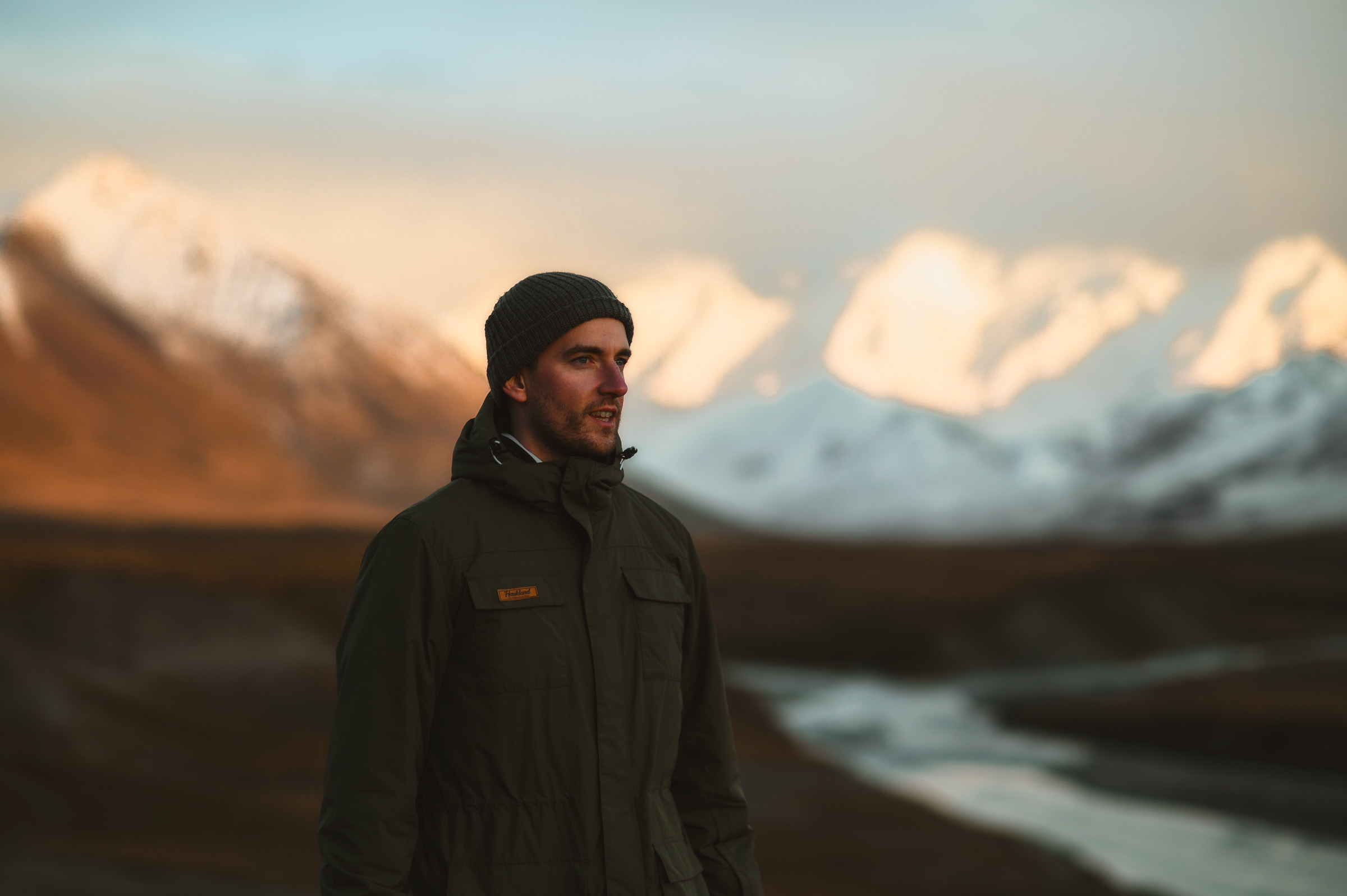 Portrait of a traveler in a black beanie before snowy mountains
