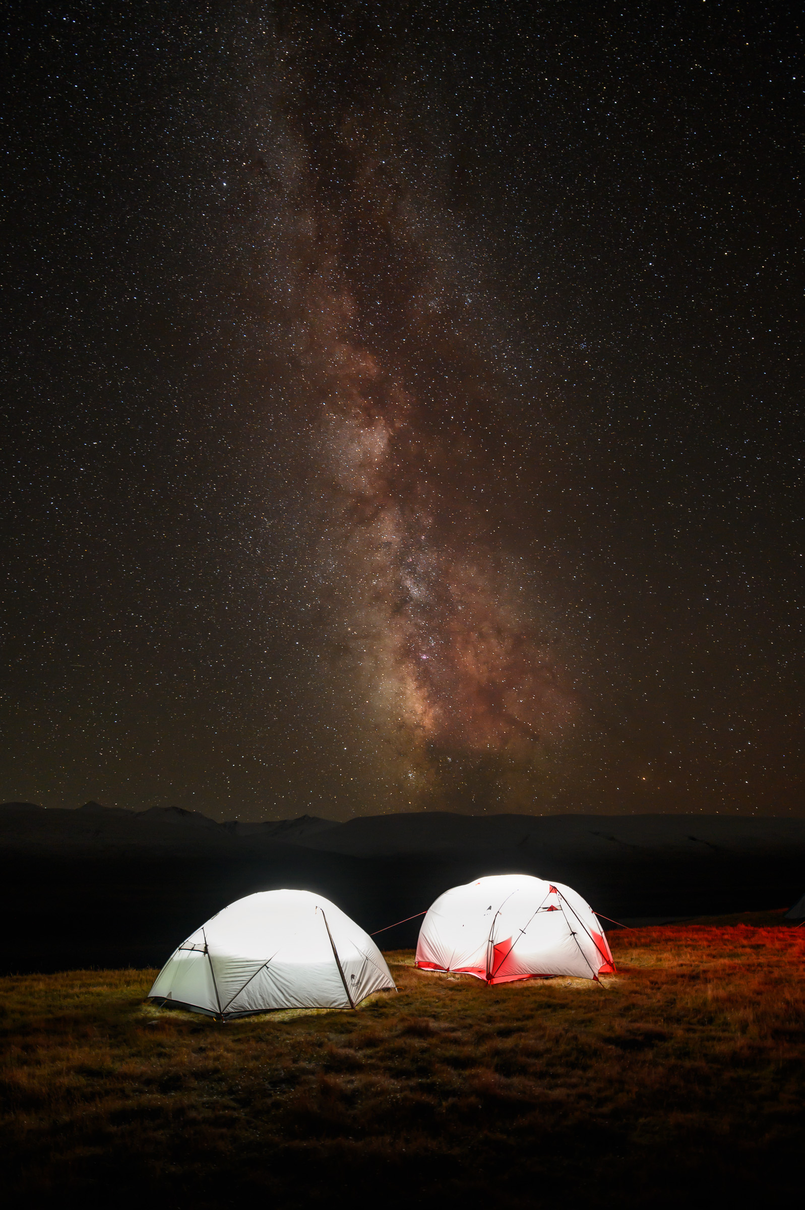 Illuminated tents beneath the Milky Way on a remote plateau