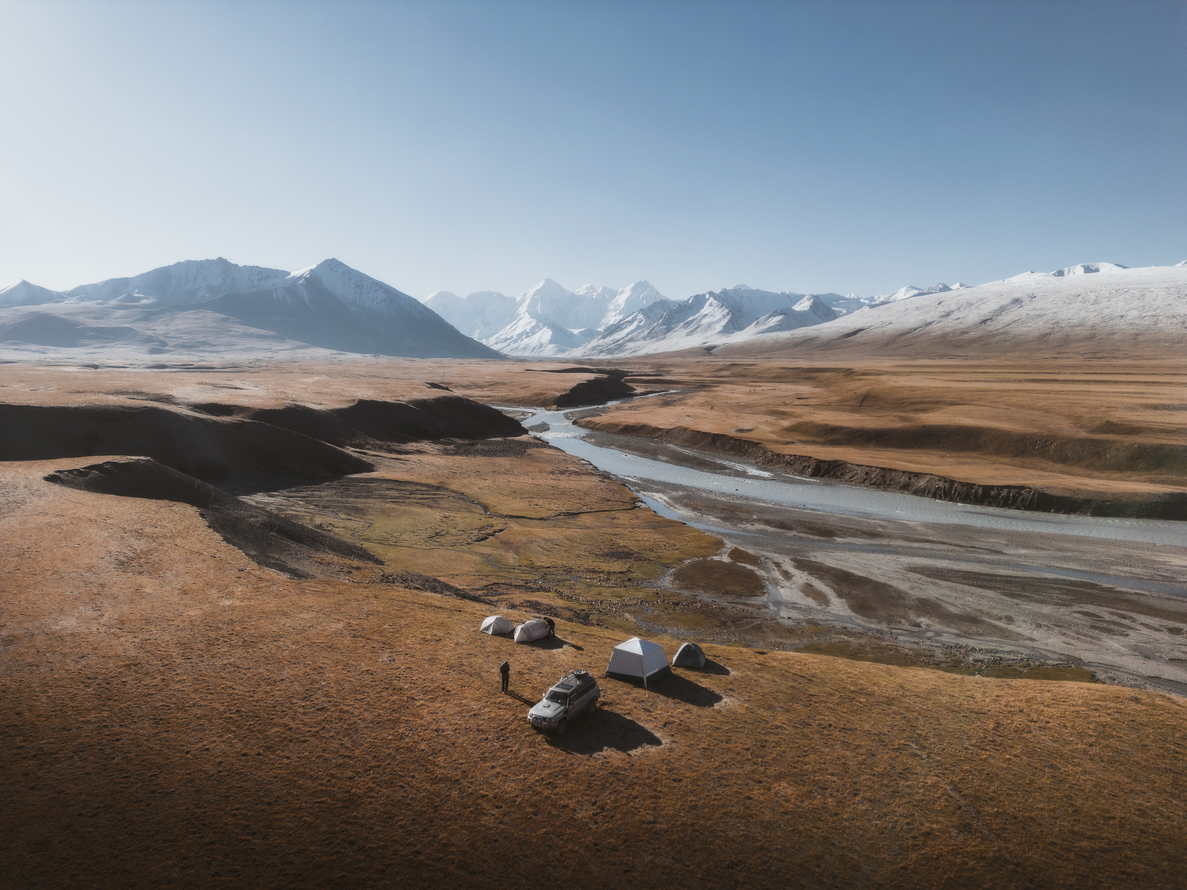 Aerial view of tents beside a braided highland river