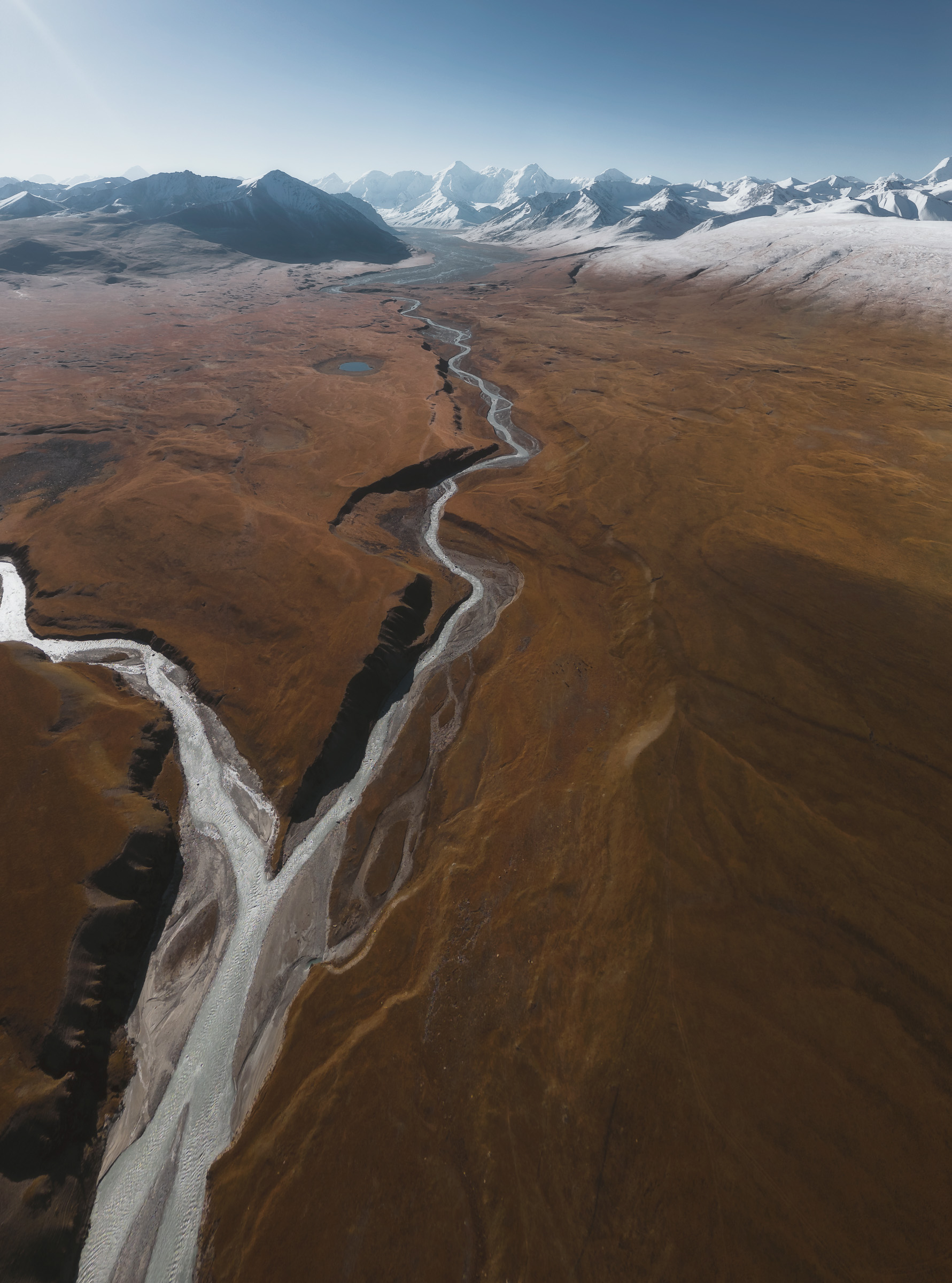 Aerial view of a braided river crossing a broad brown plain