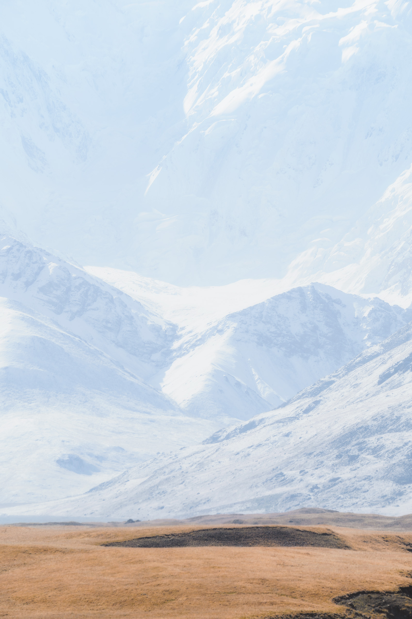 Layers of snow-covered mountains fading into bright mist