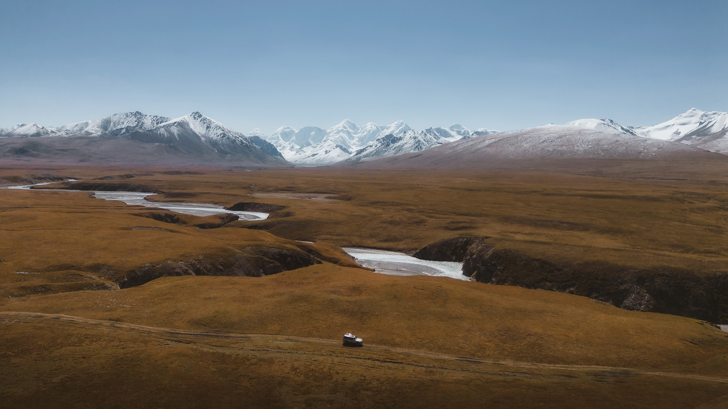 White off-road vehicle beside a winding highland river