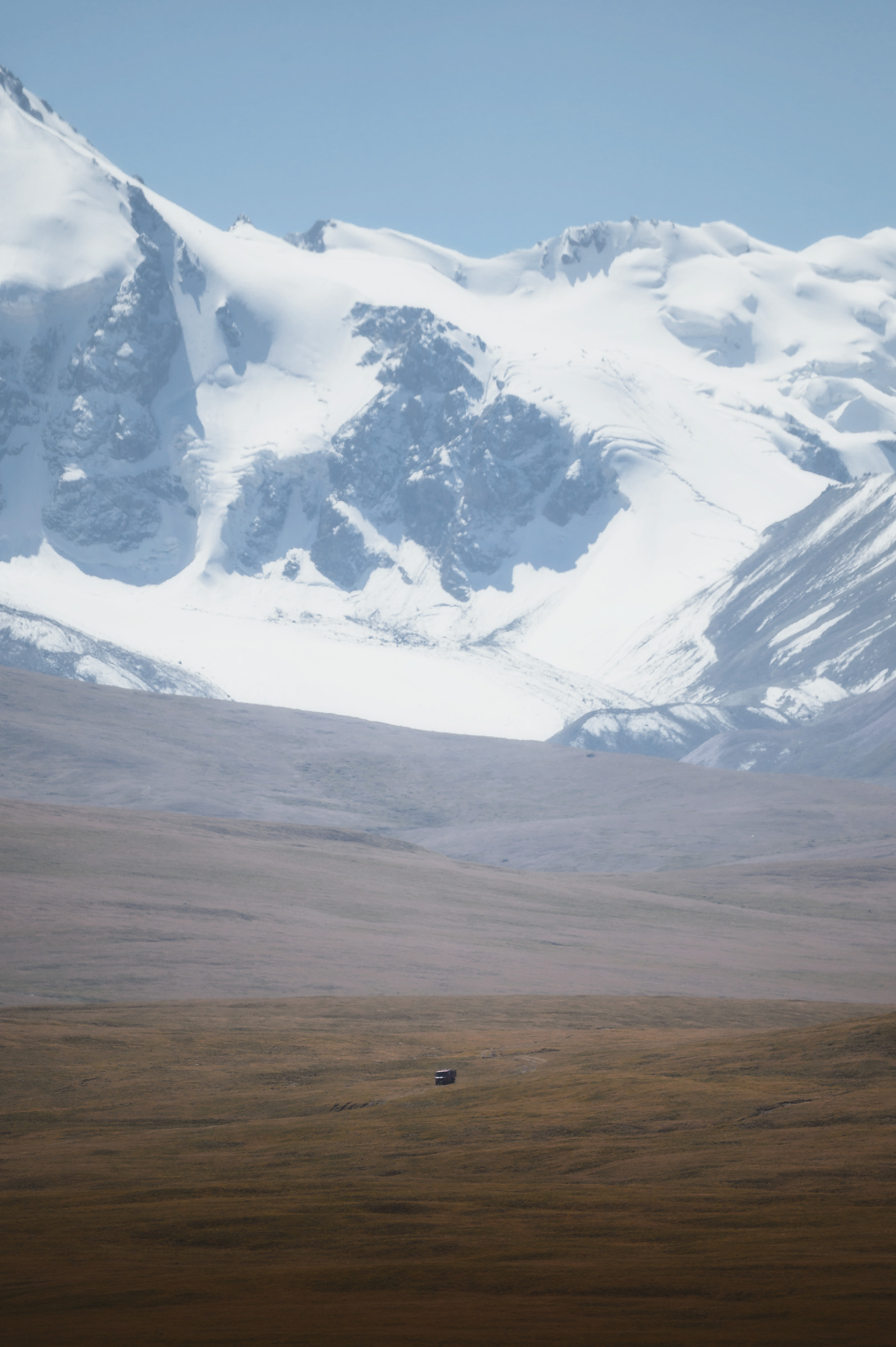 Glacier-covered mountain rising above a brown plateau