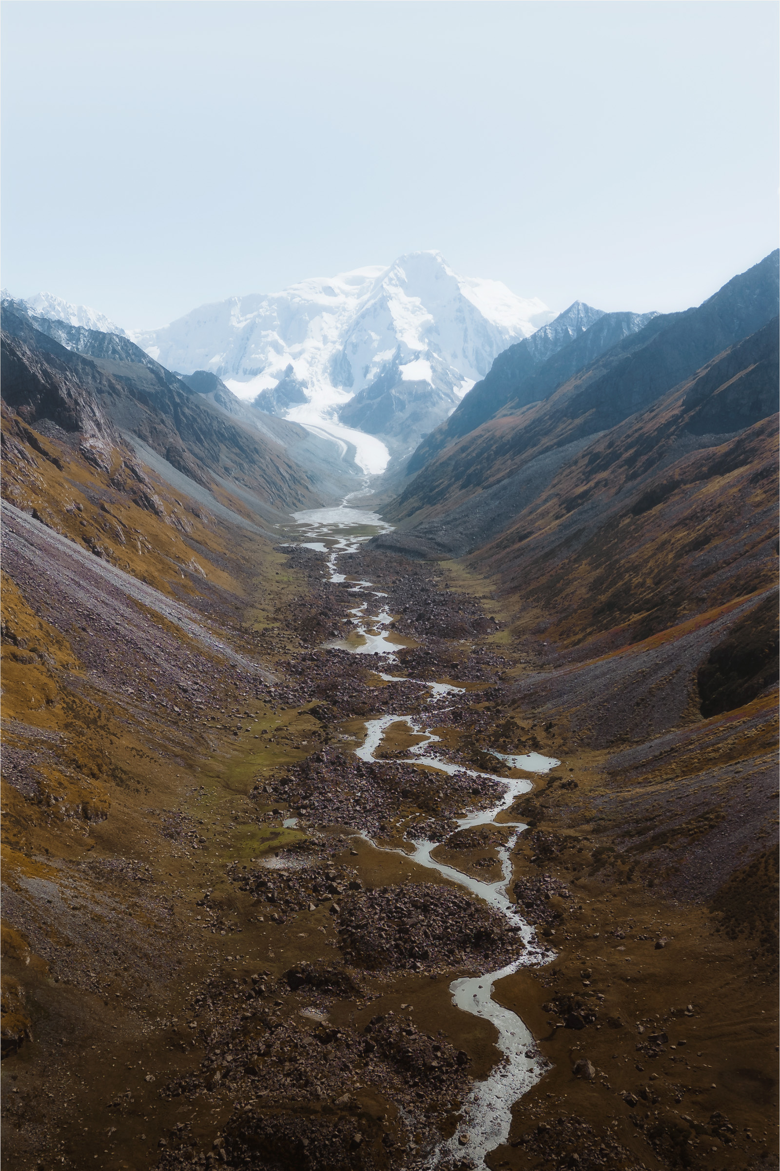 Narrow river leading through a valley toward snowy peaks