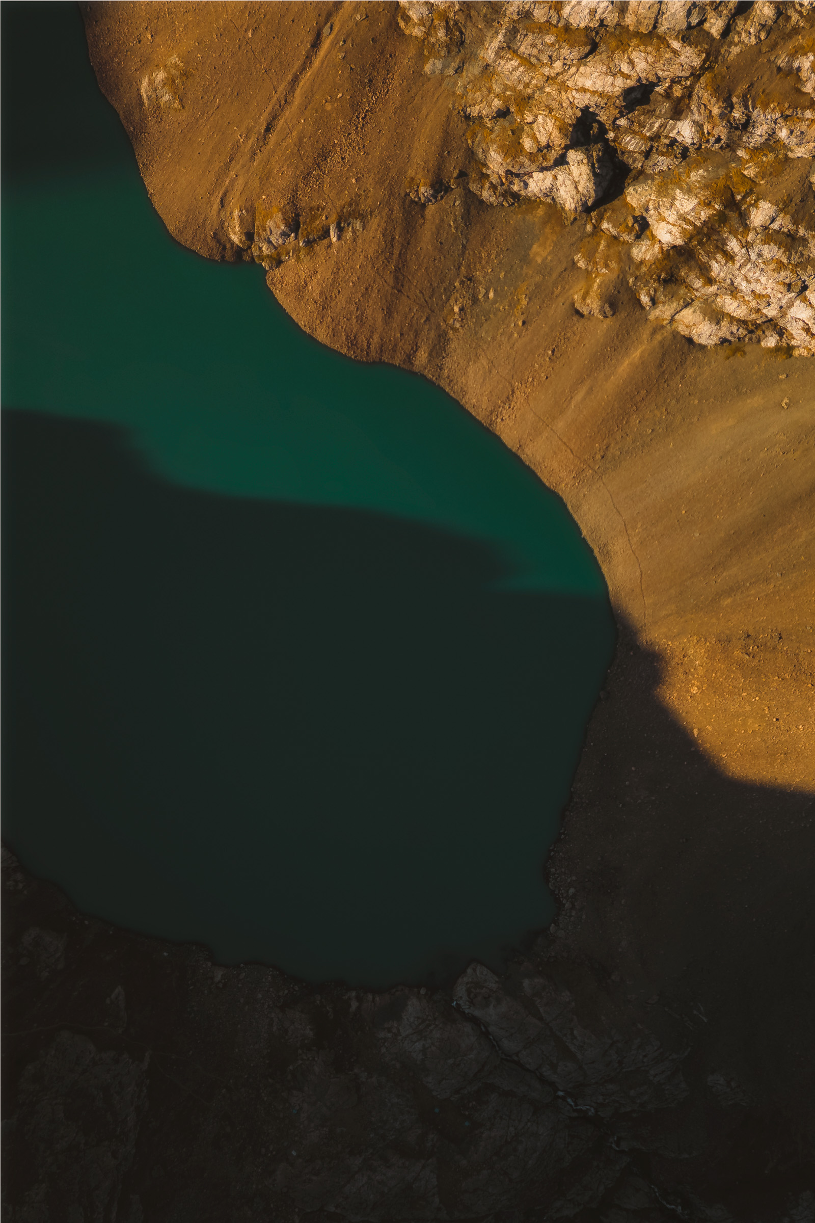 Top-down view of a turquoise lake between ochre cliffs