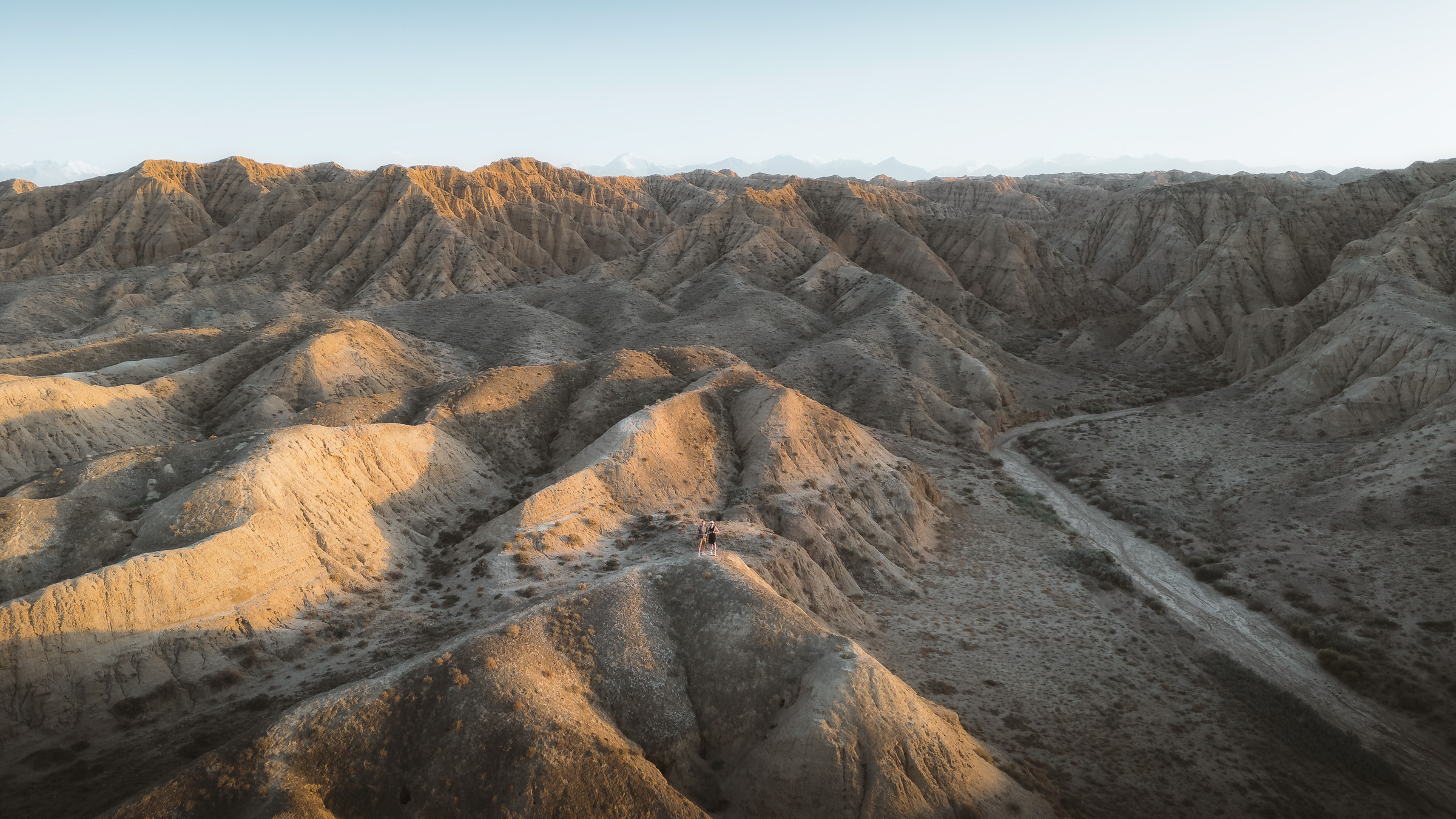 Wide aerial view of gray badlands and sunlit ridges