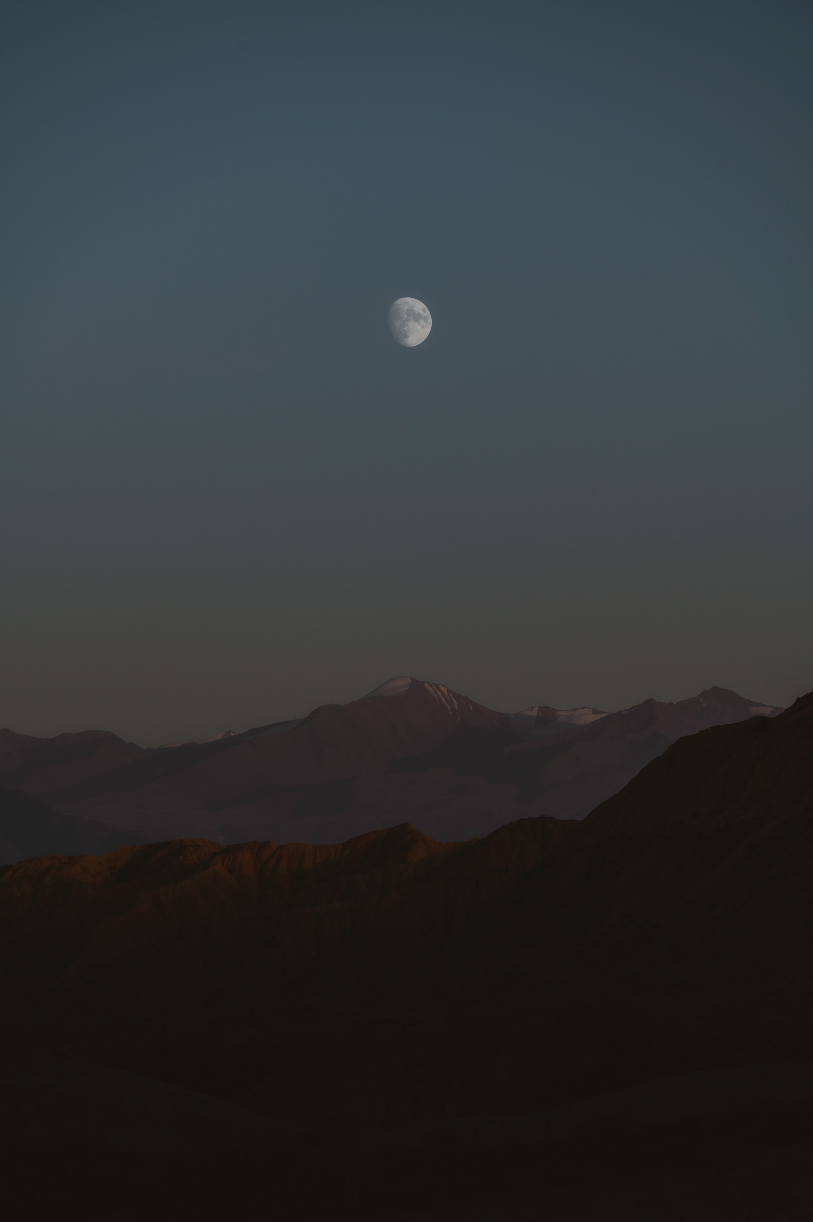 Half moon above dark mountain silhouettes