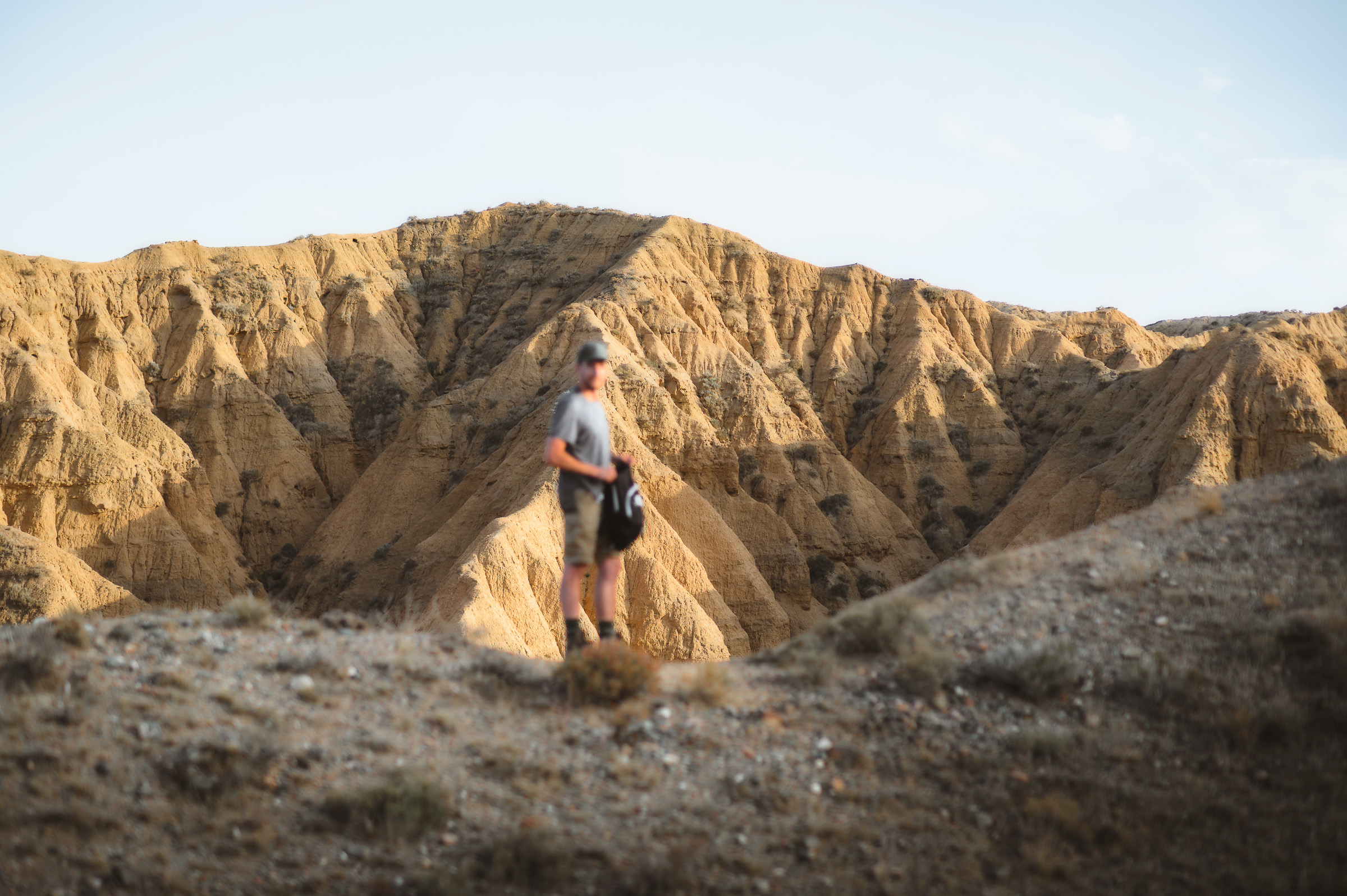 Traveler in a cap walking across pale eroded hills