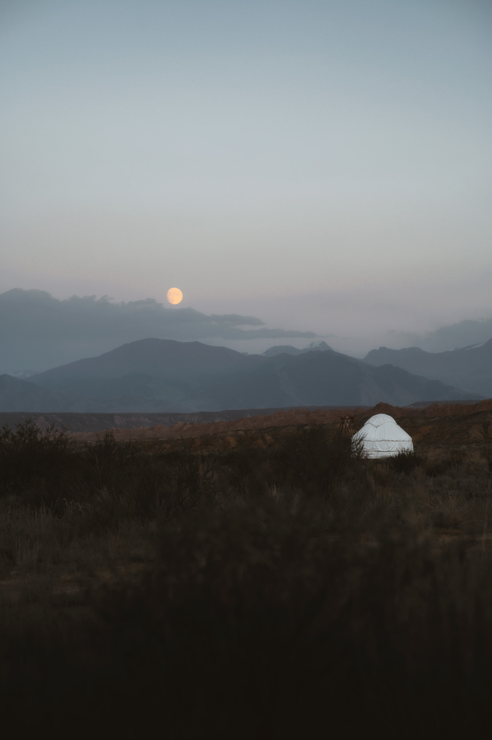 Moon rising behind a lone white tent on the steppe