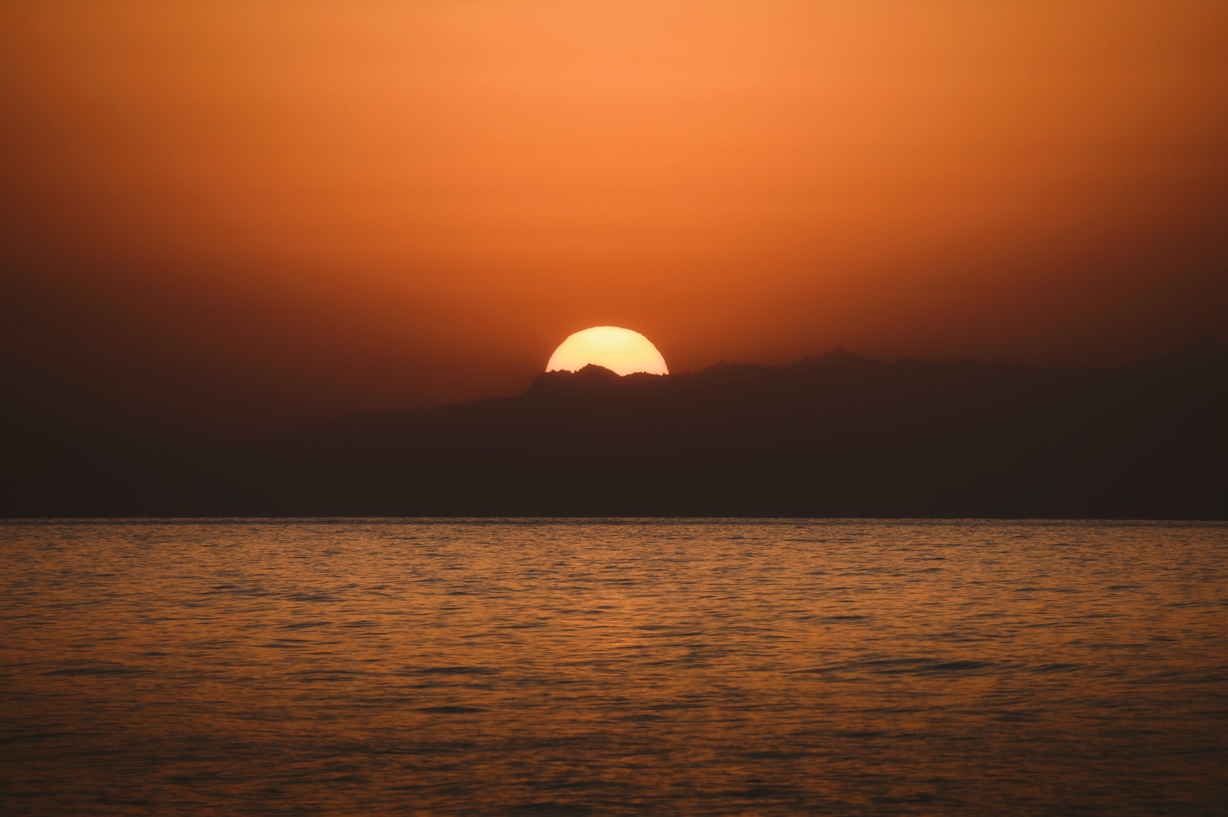 Sun setting across the calm surface of a mountain lake