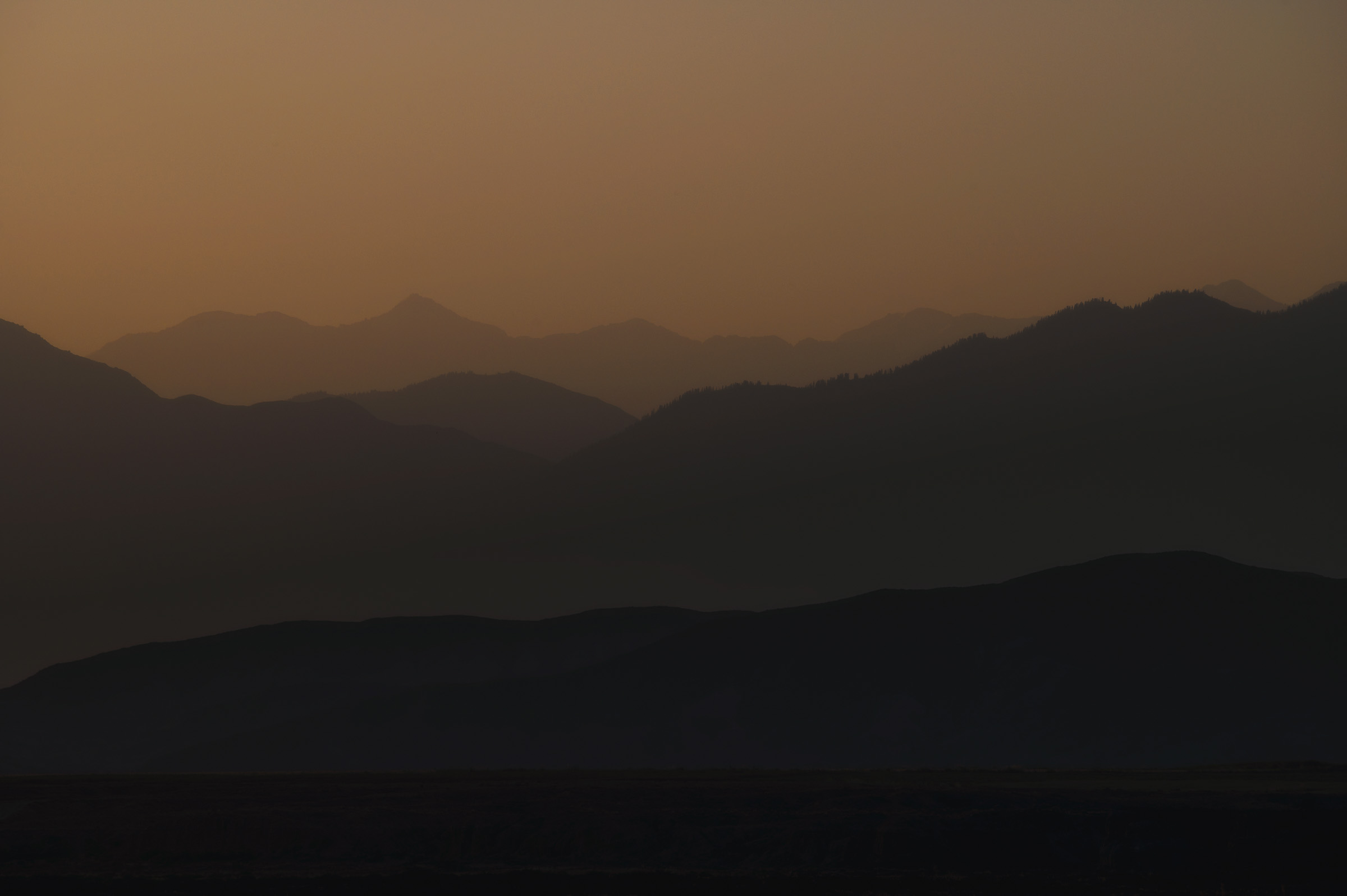 Layers of mountain silhouettes fading into warm haze