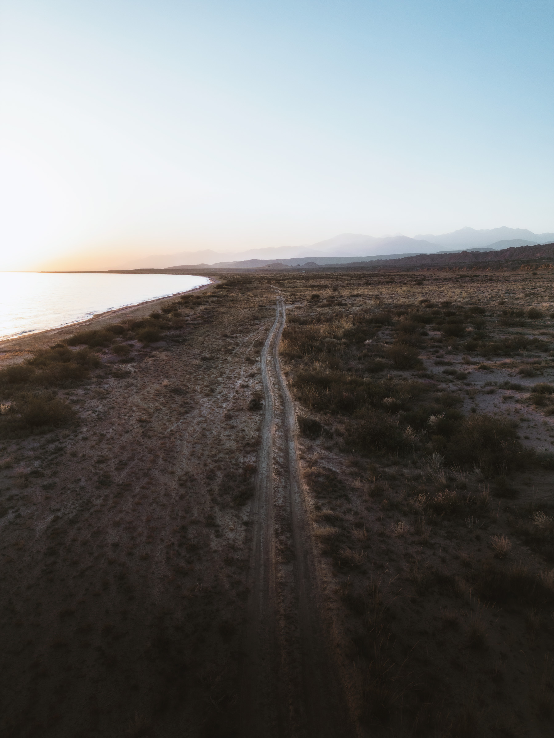 Tire tracks following the shore of a remote mountain lake