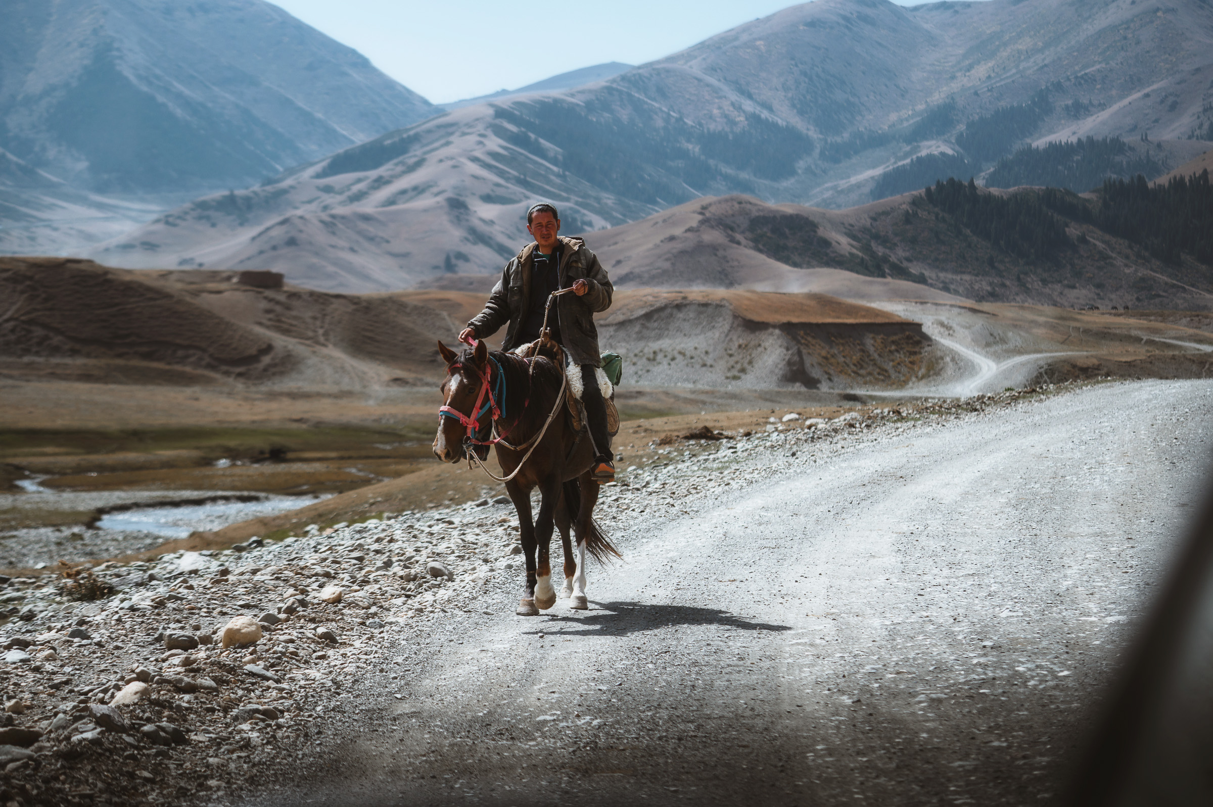 Horseman riding along a gravel road through the mountains