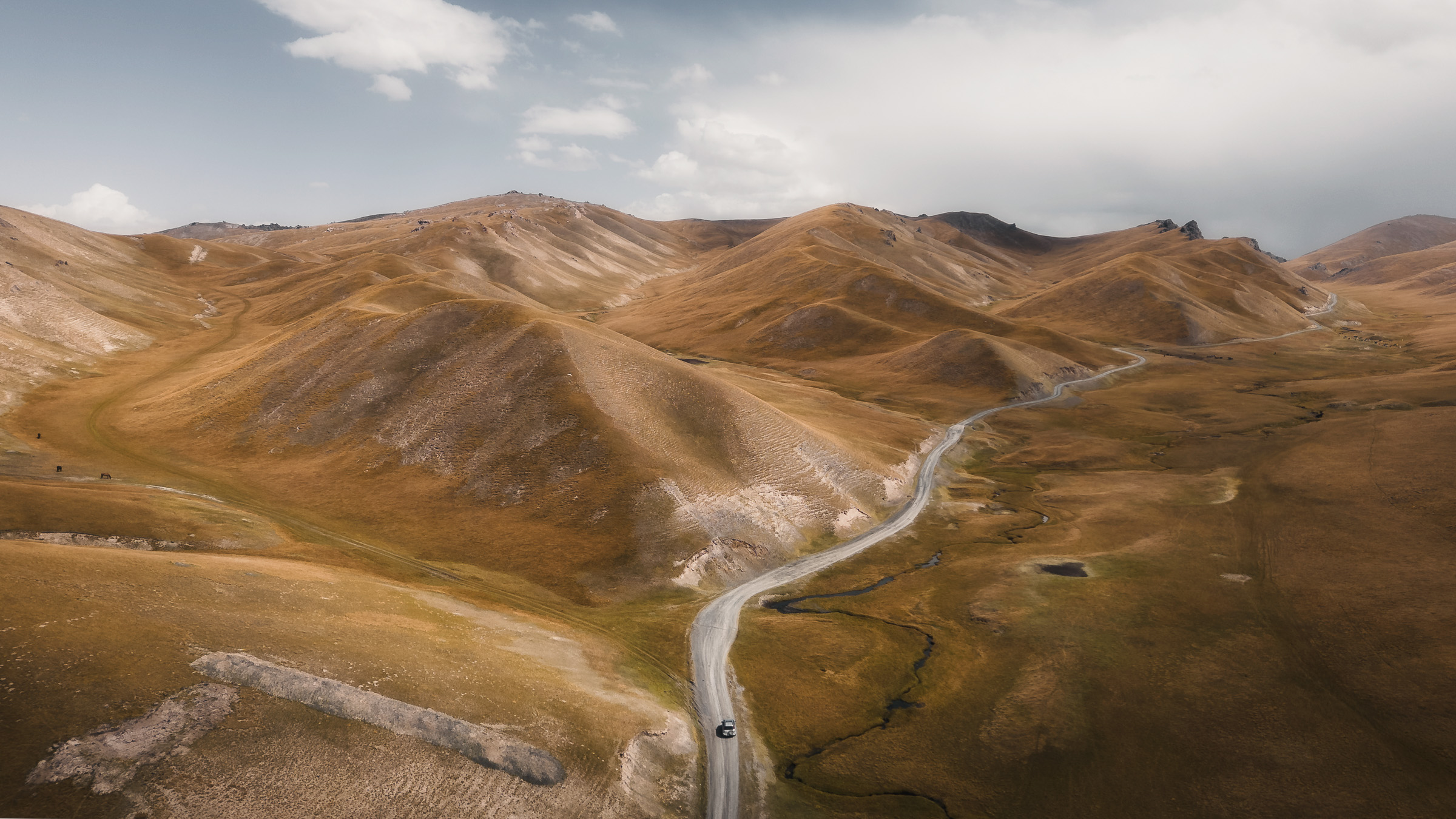 Aerial view of a winding road through a golden mountain valley