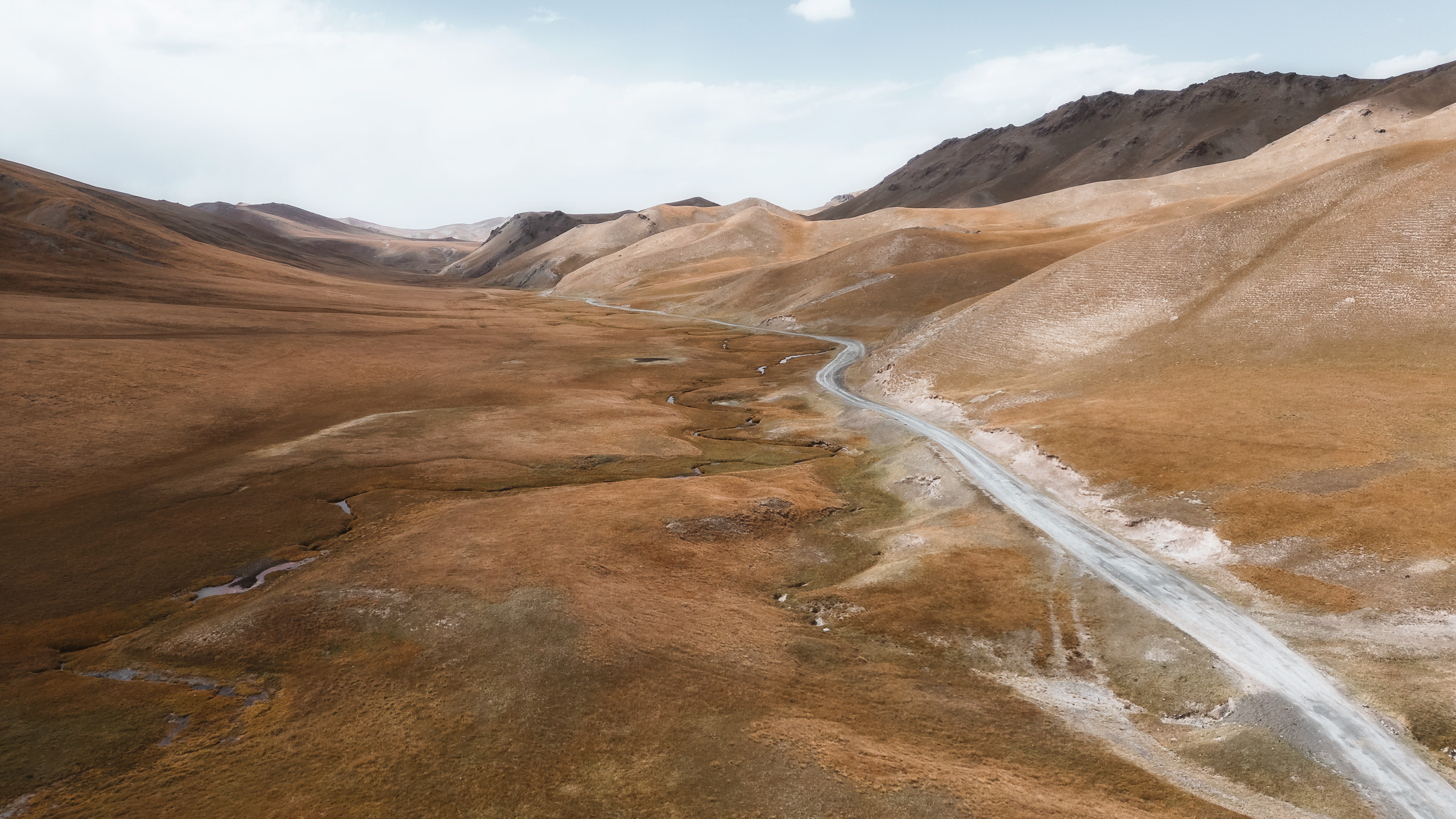 Dirt road winding across a barren highland plateau
