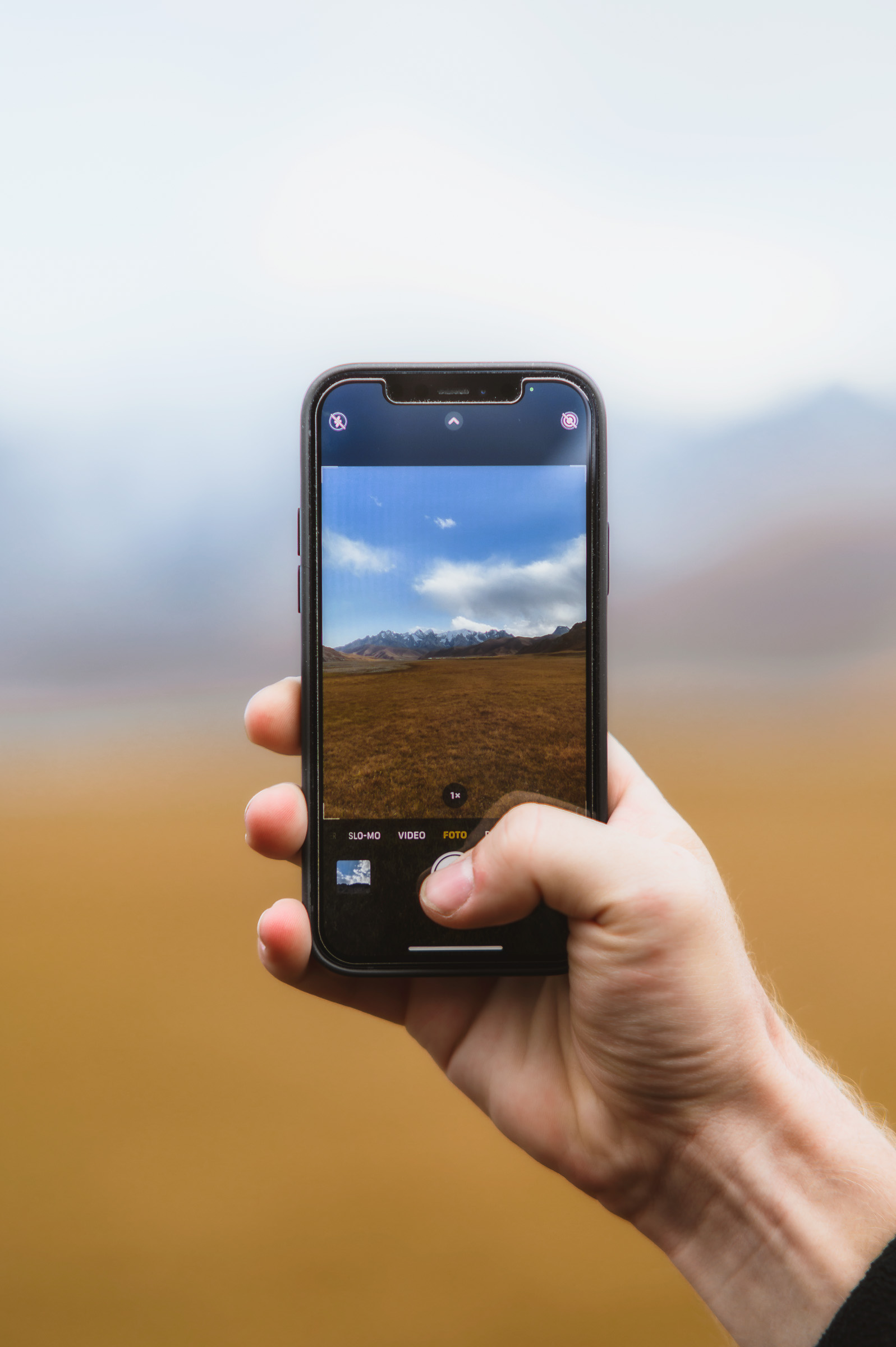 Hand holding a phone to photograph the mountain landscape
