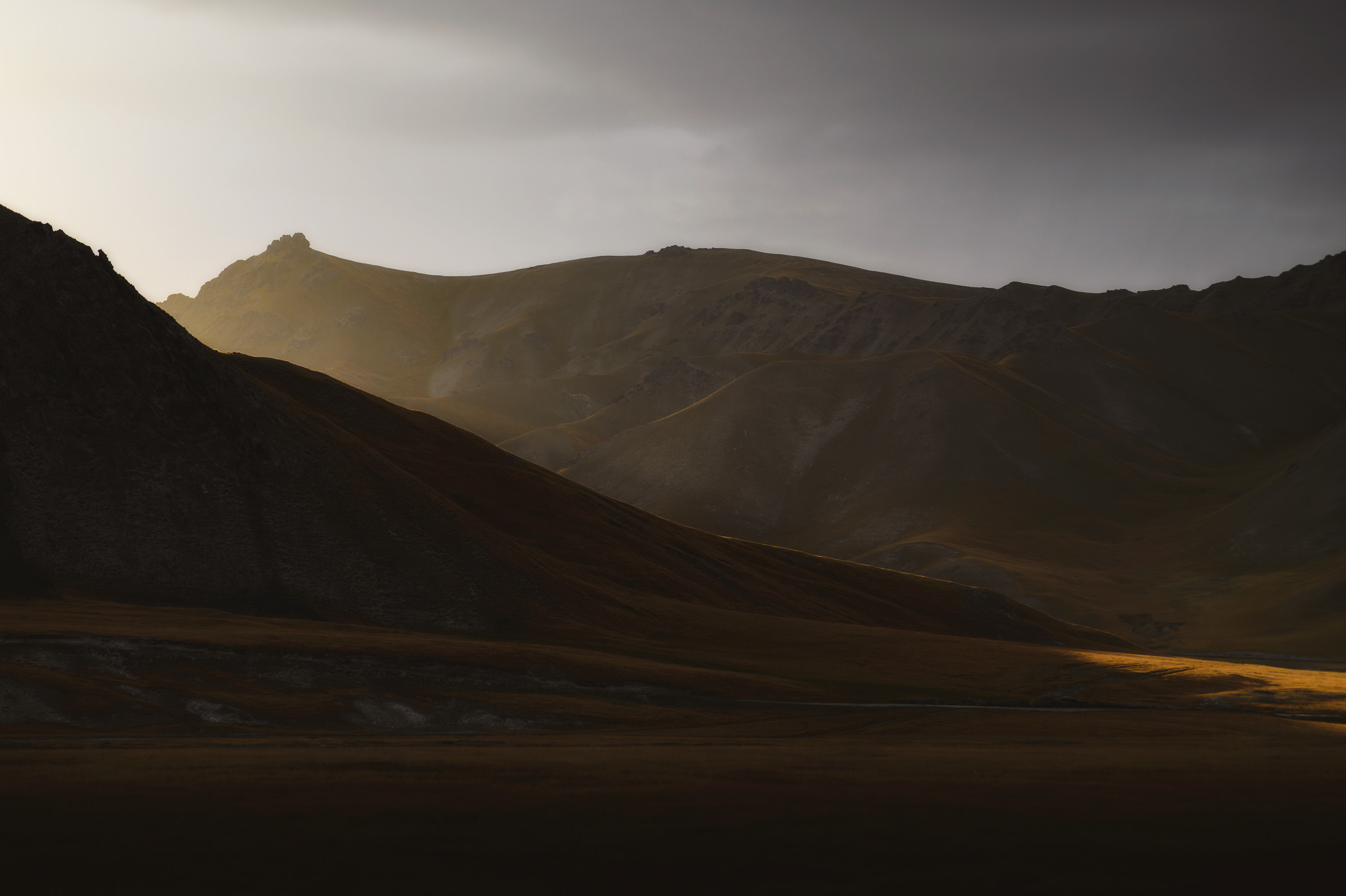Sunbeams breaking through clouds over shadowed ridges