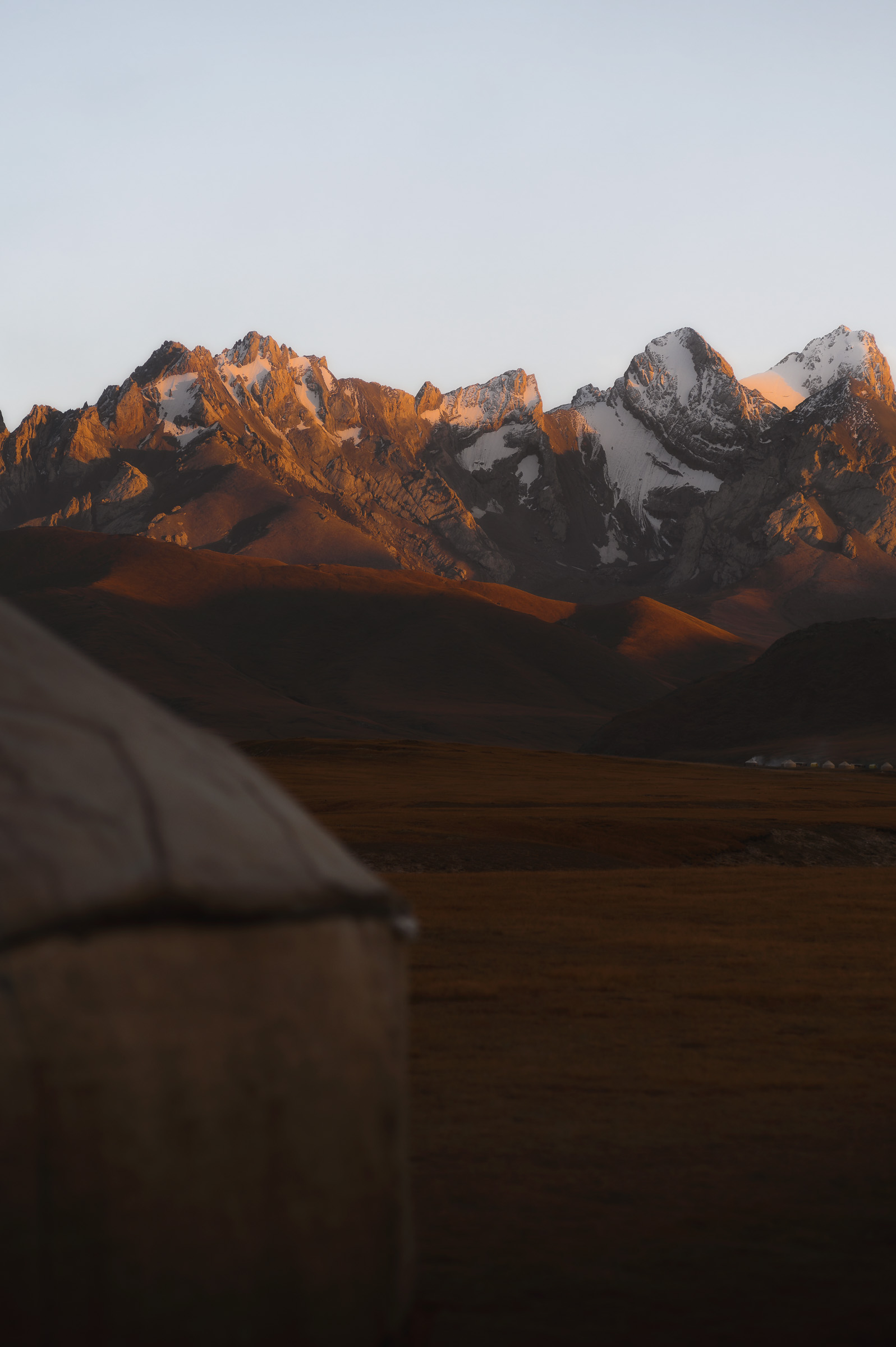 White yurt against orange-lit snowy mountains