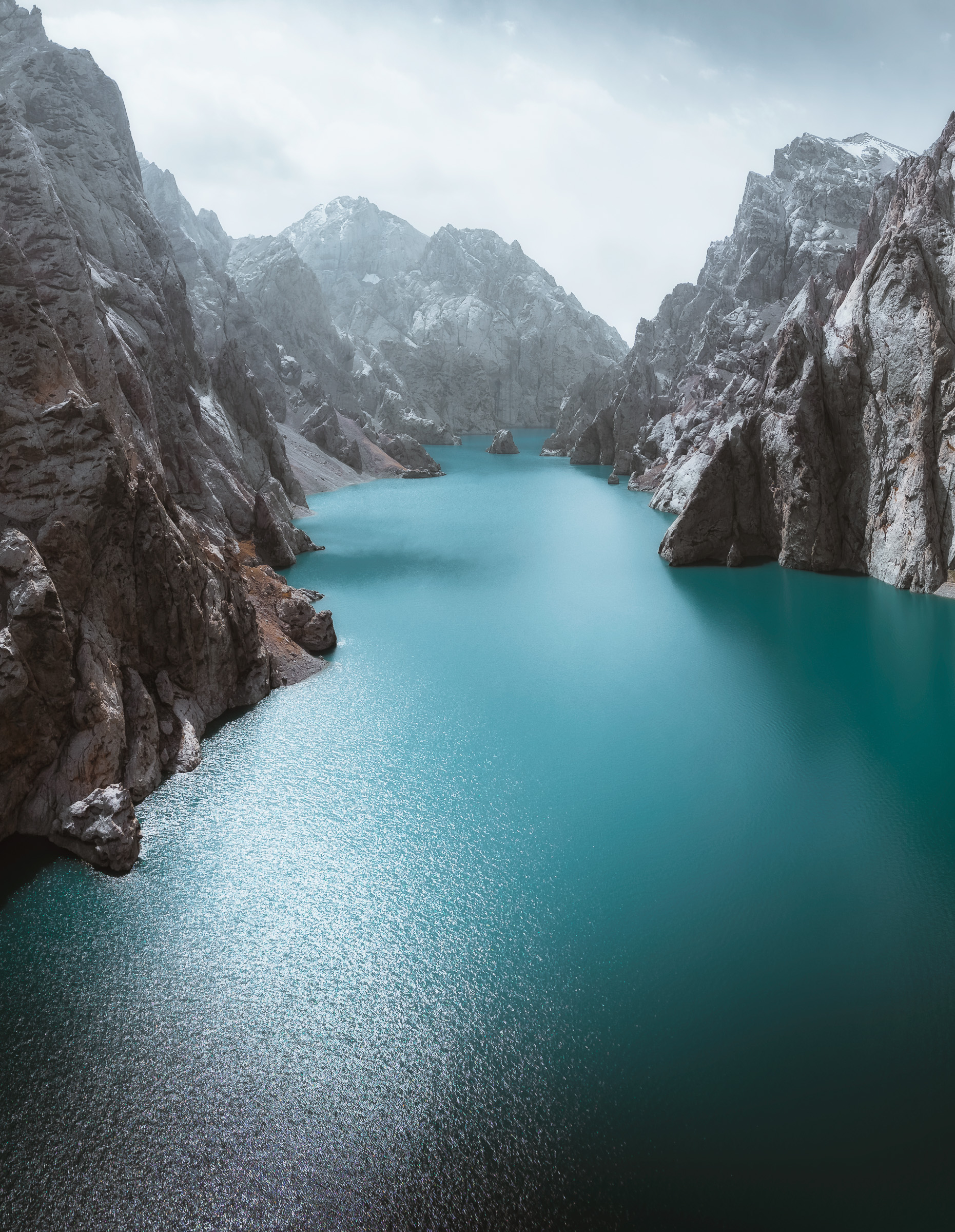 Turquoise canyon lake enclosed by steep gray cliffs