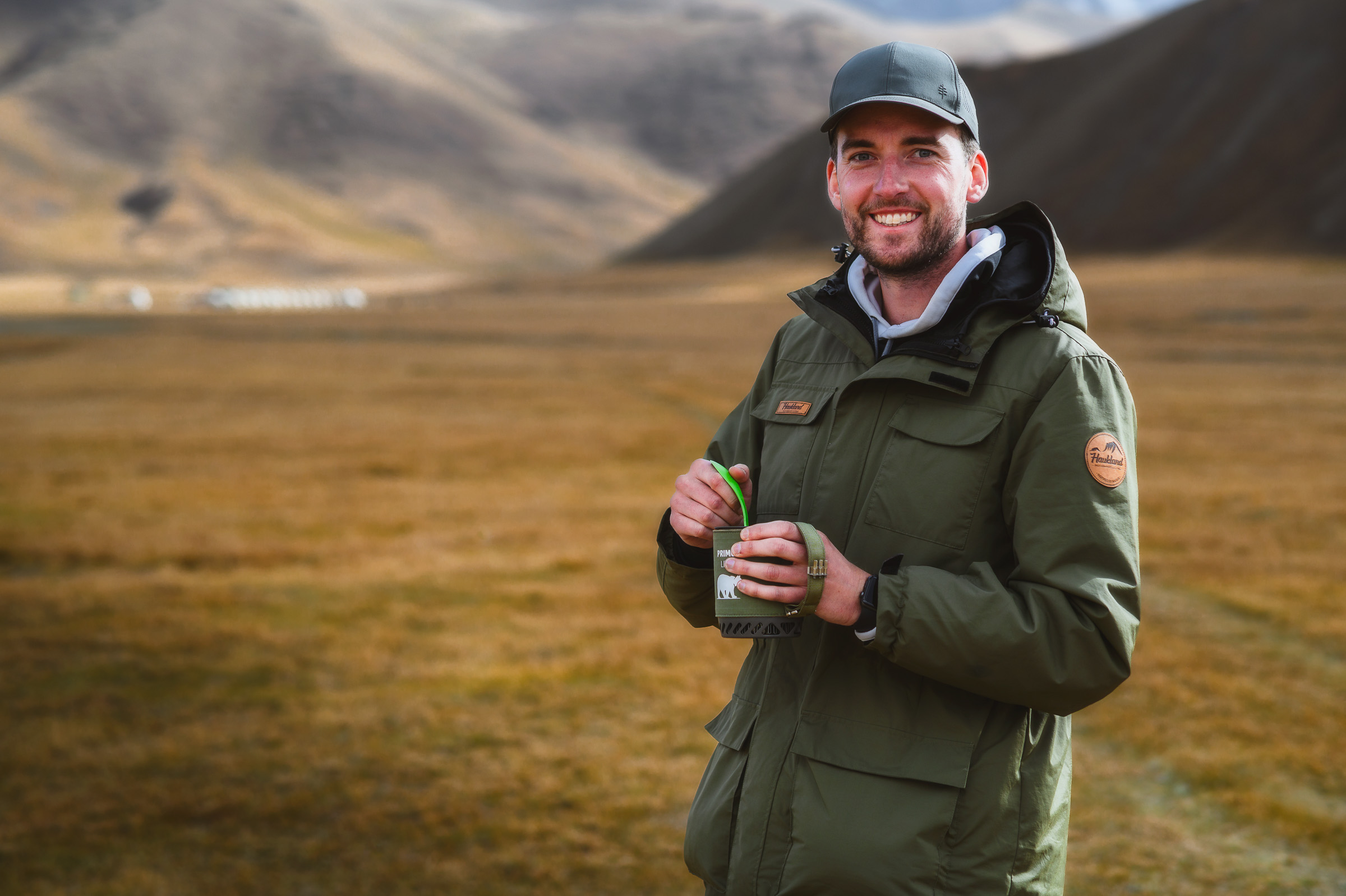 Smiling traveler holding a camera in a mountain valley