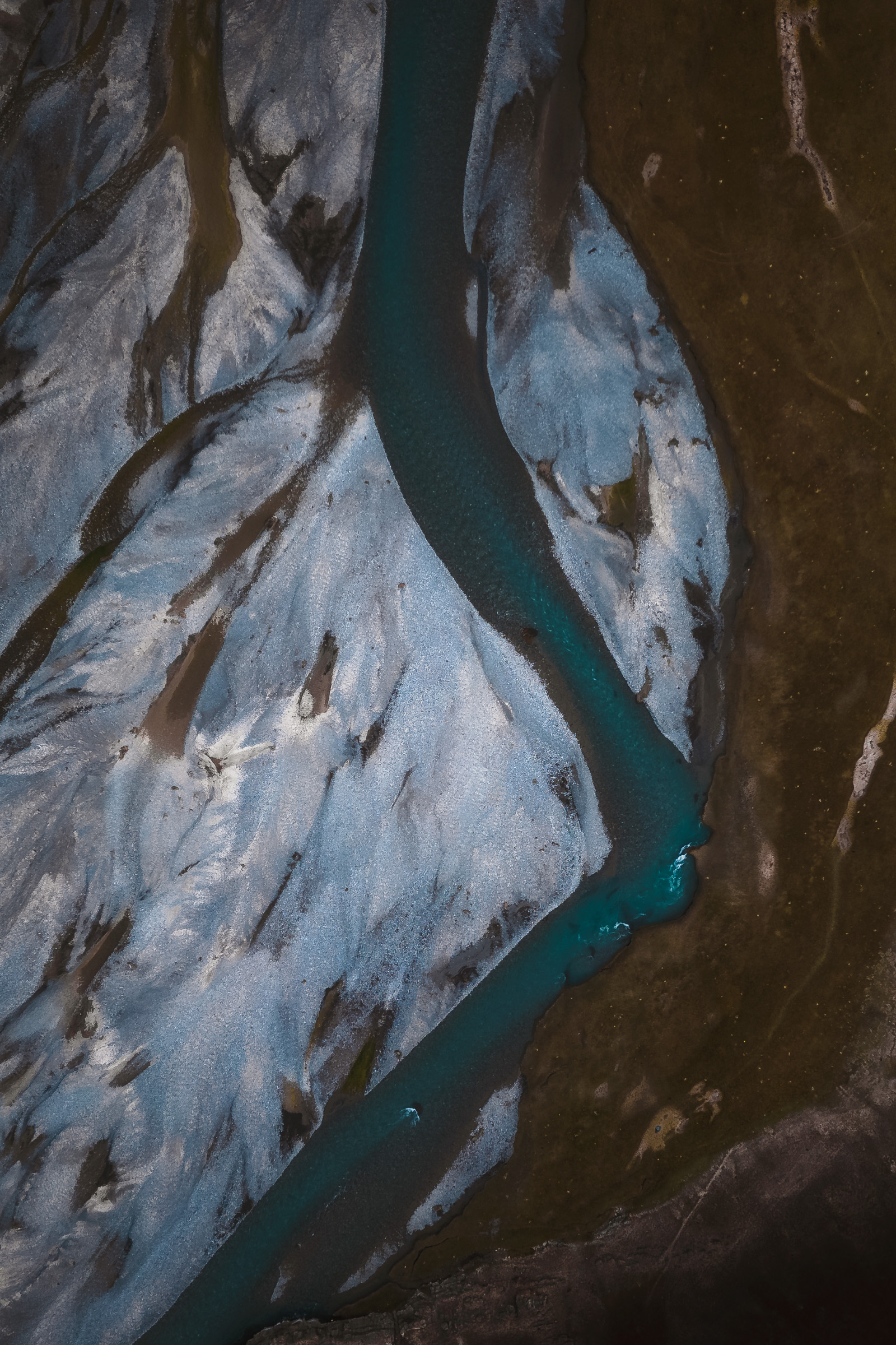 Aerial view of a turquoise river through gray braided channels