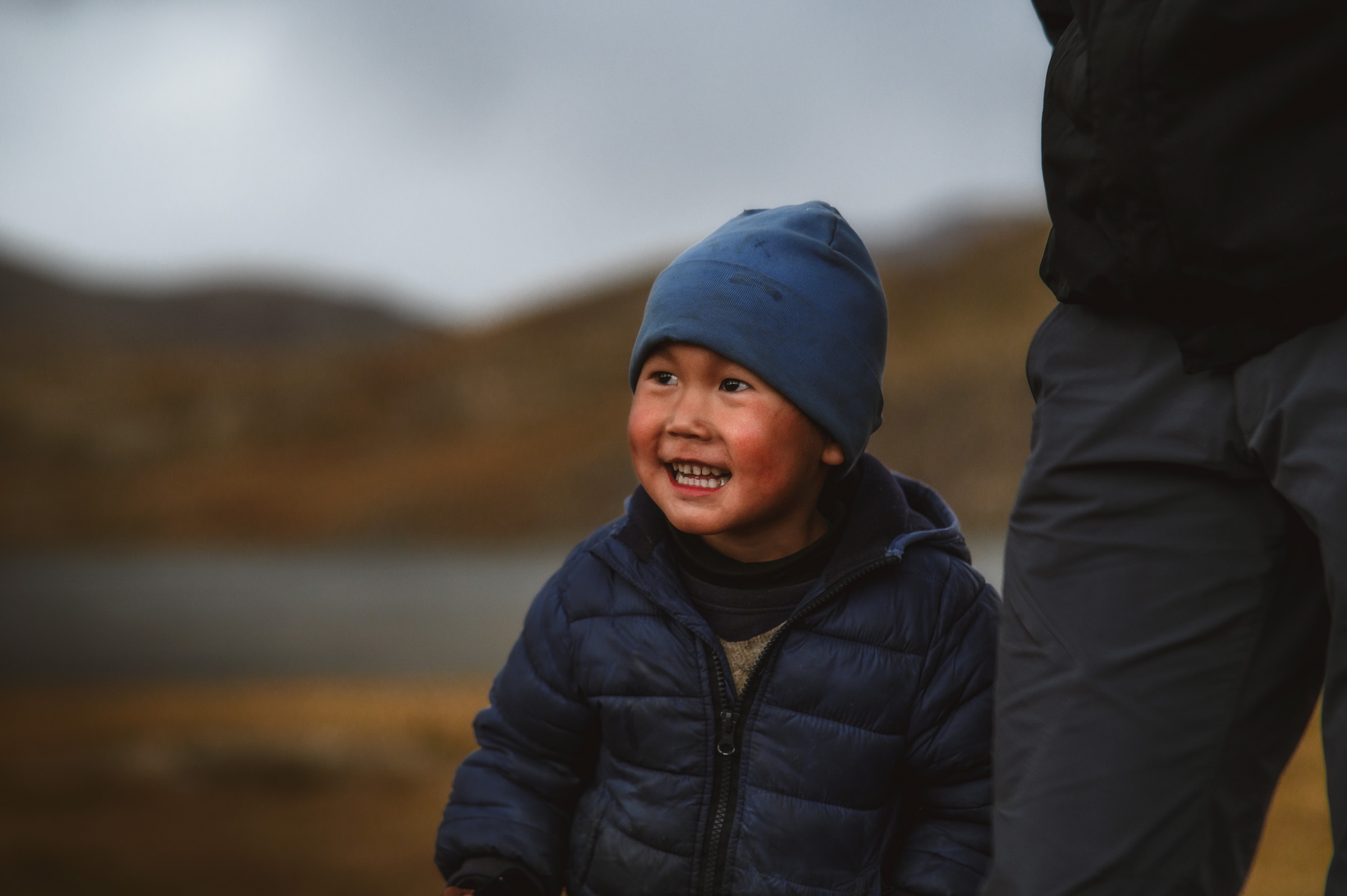 Smiling young child in a blue hat on the highland plain