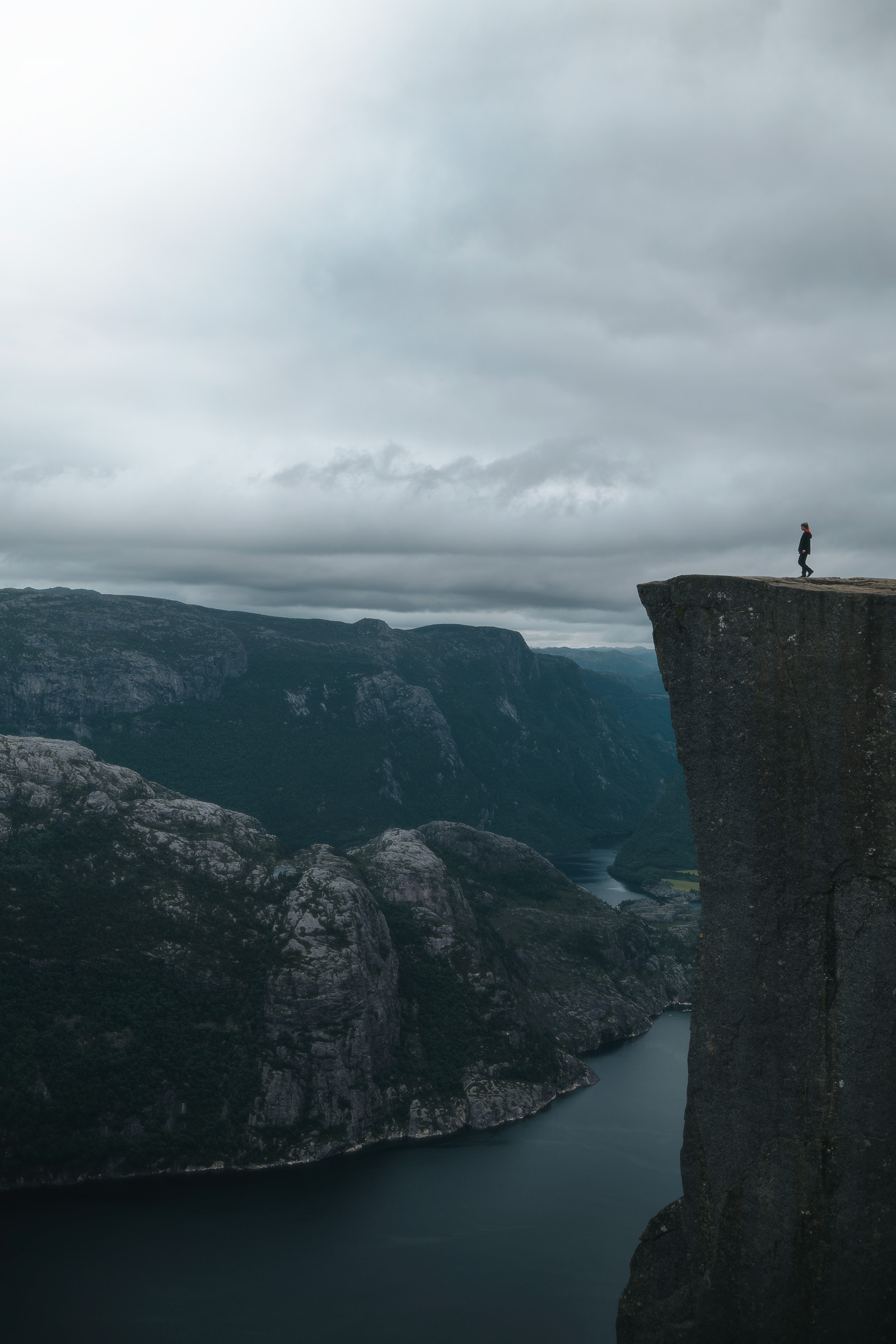 A lone hiker stands on Preikestolen high above Lysefjord