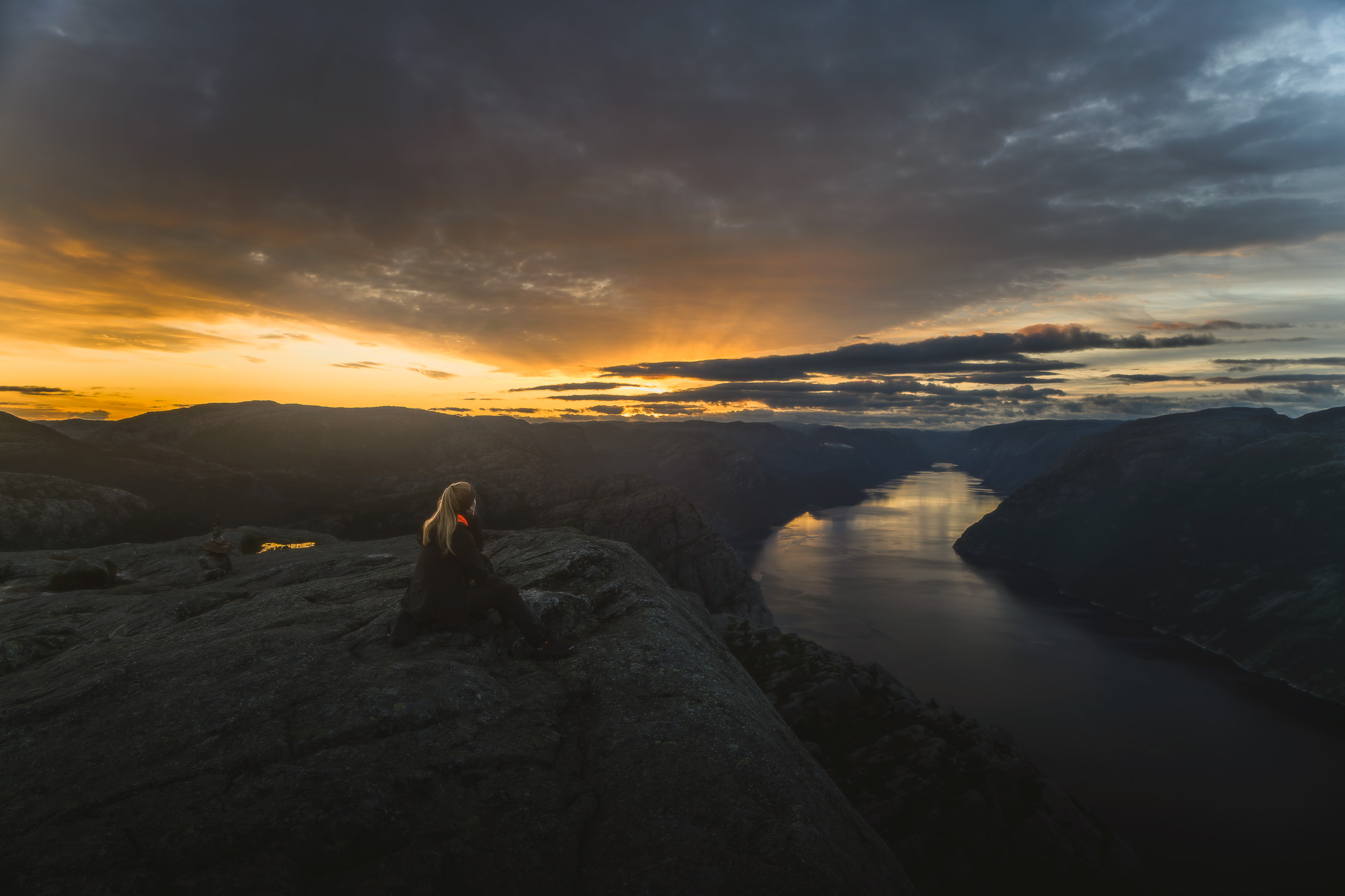 Hiker watches the sunrise over Lysefjord from Preikestolen