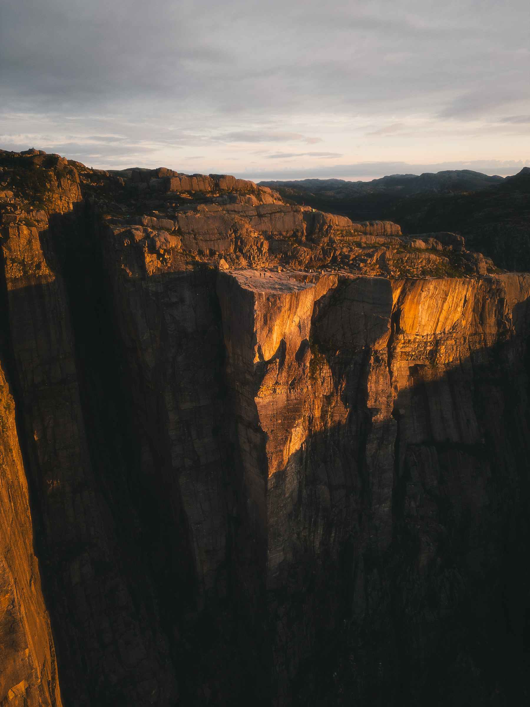 Sunlit Preikestolen cliff rising above the shadowed fjord