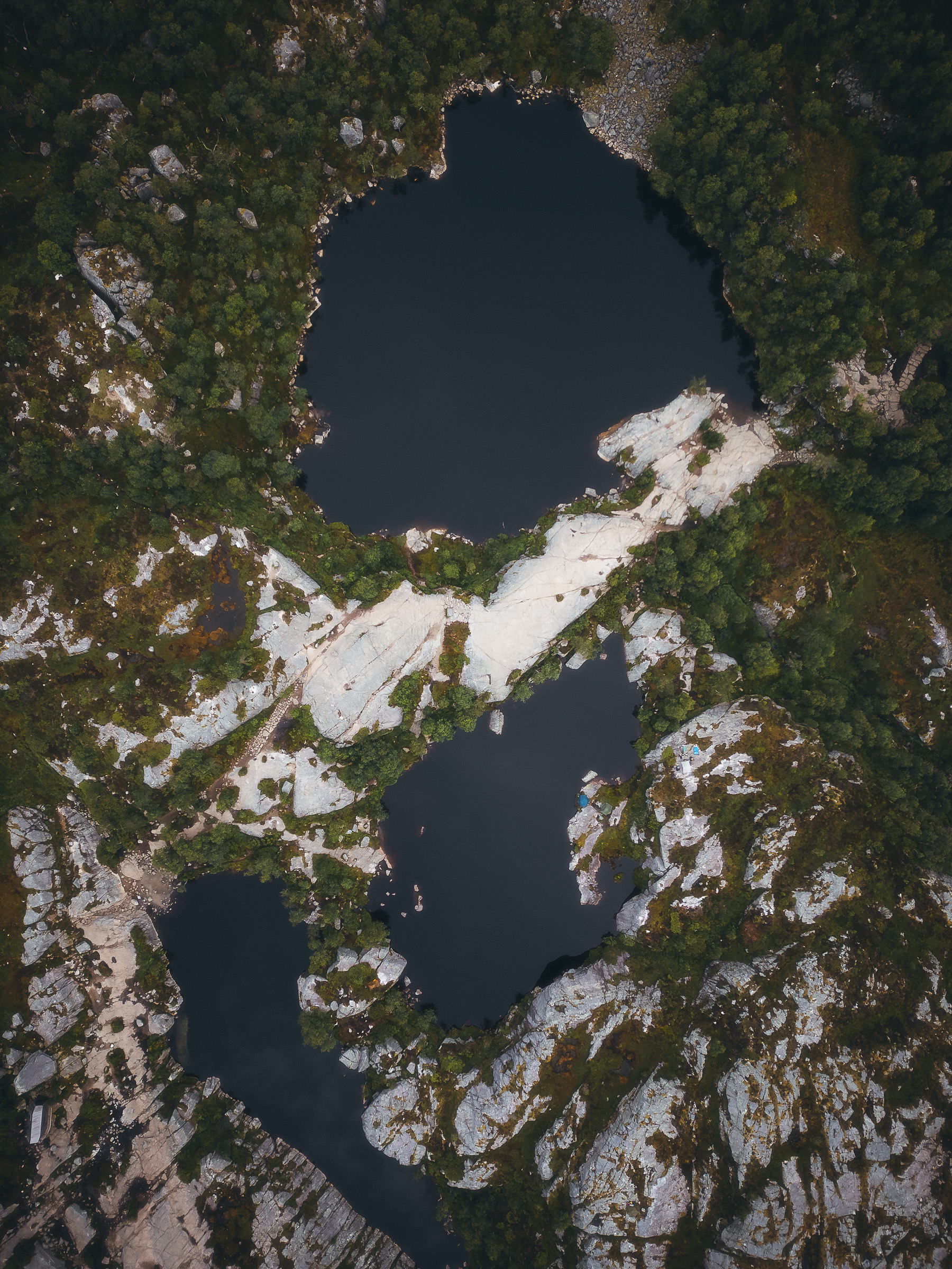 Top-down aerial view of dark mountain lakes among pale rocks