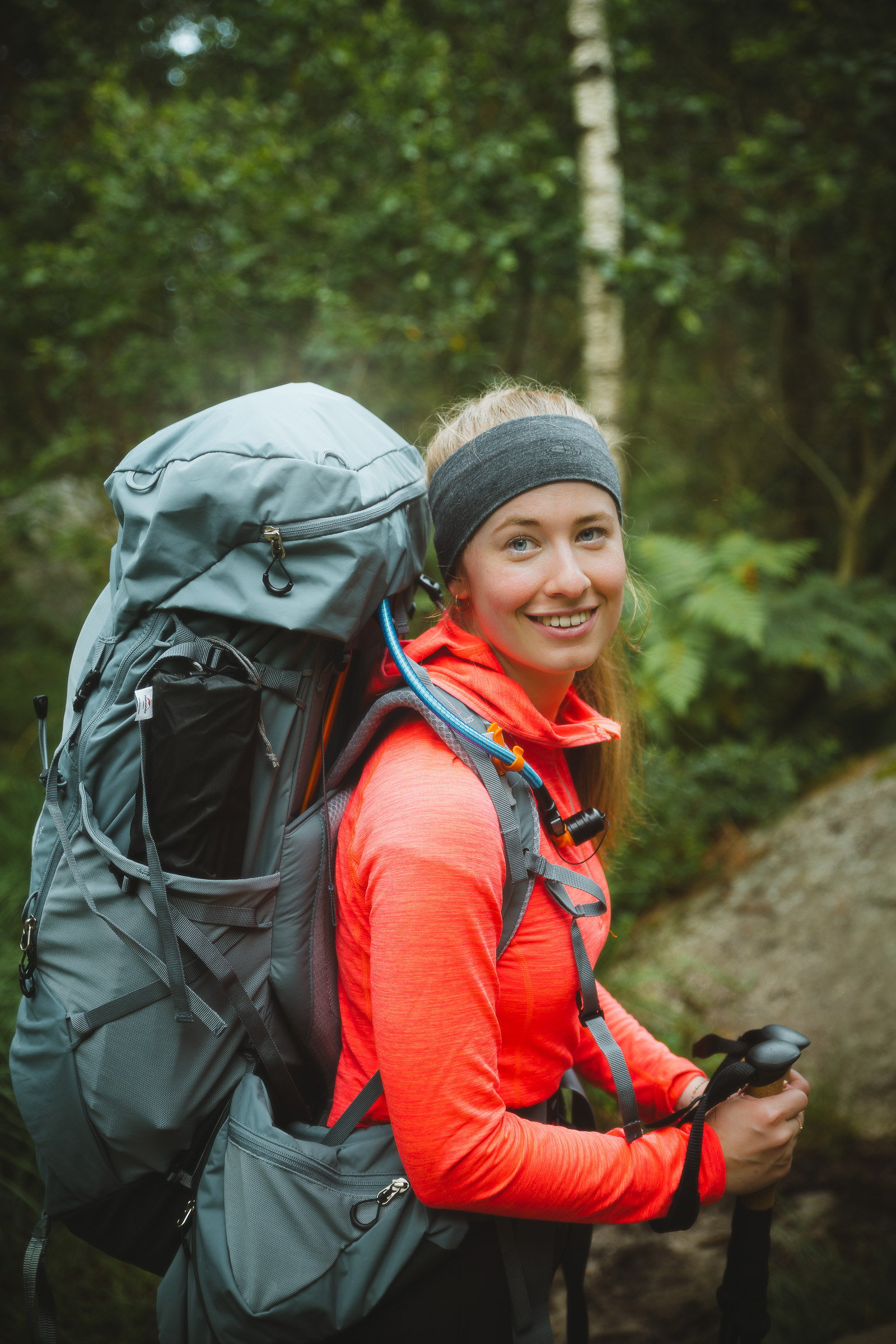 Woman hiker with a large backpack smiling on a forest trail