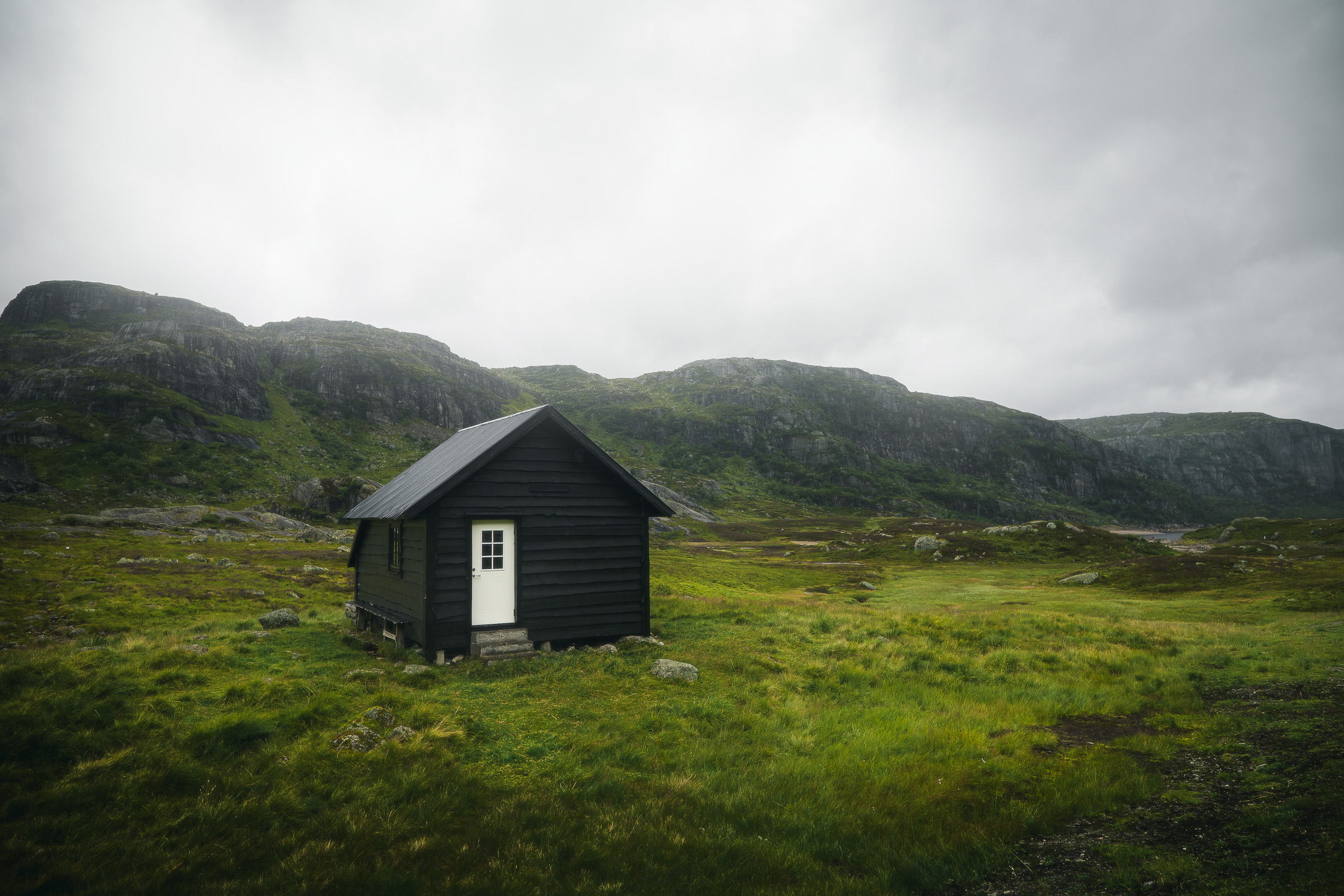 Small black cabin in rain-soaked green mountains