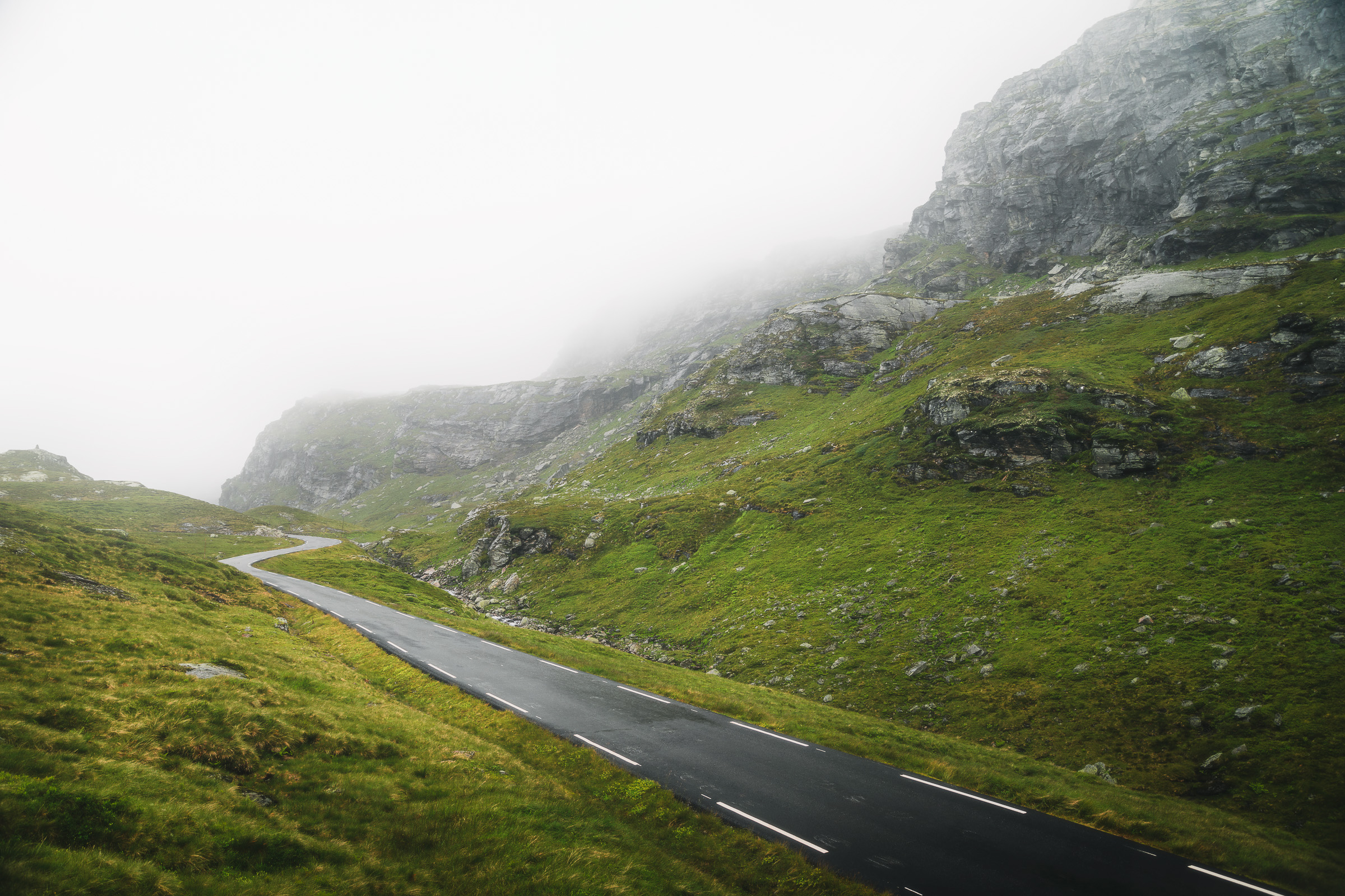 Winding mountain road disappearing into dense fog