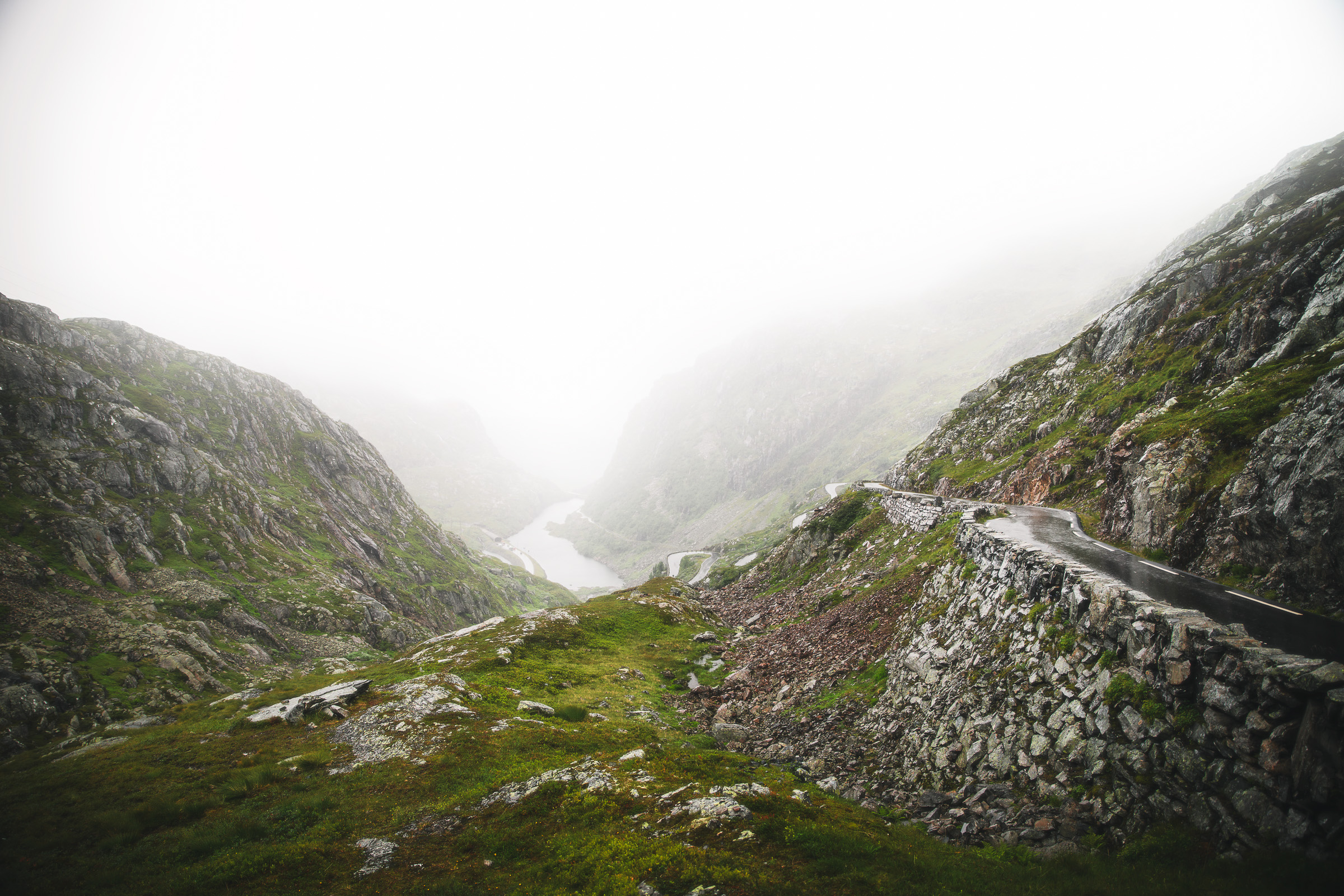 Stone-lined road winding through a green rocky mountain pass