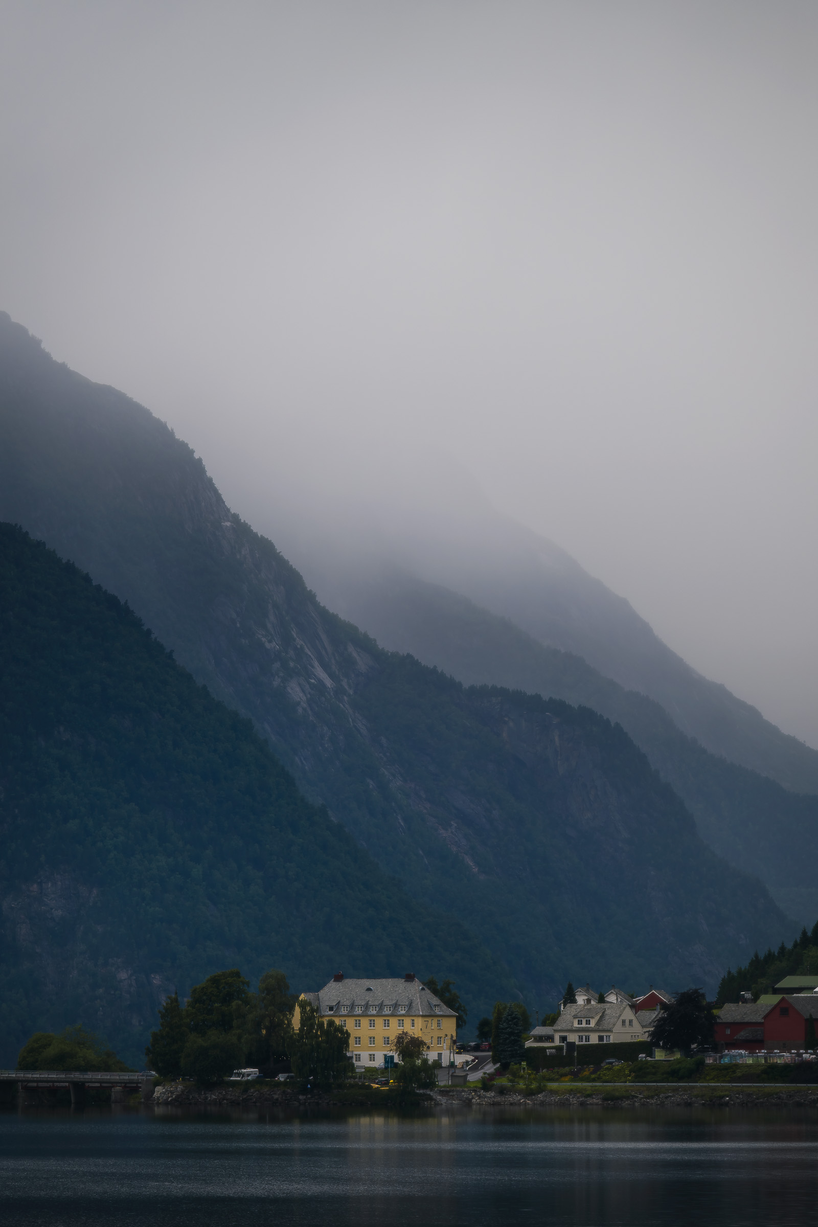Lakeside village beneath a mountain hidden by low clouds