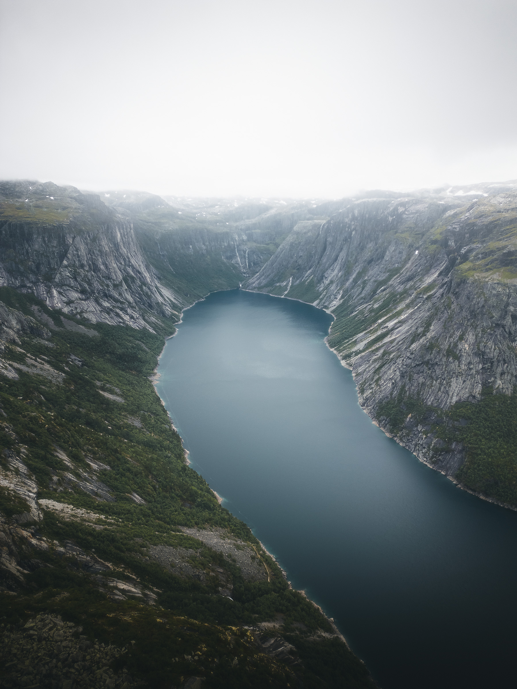 Mountain lake framed by steep slopes beneath an overcast sky