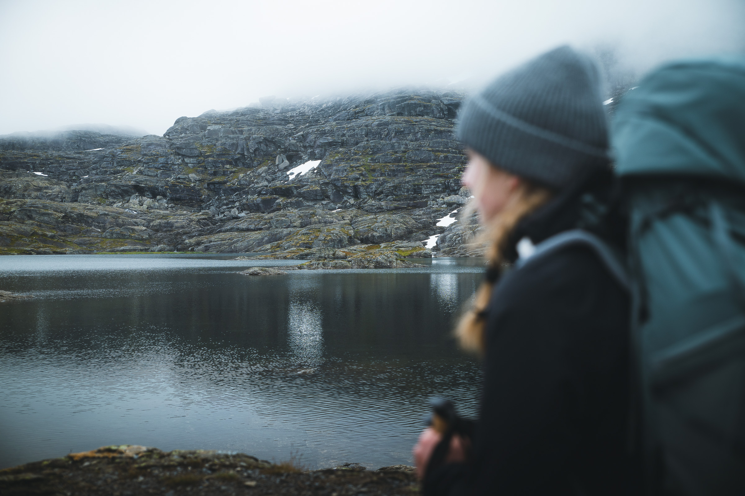 Woman hiker beside a still alpine lake on the Trolltunga trail