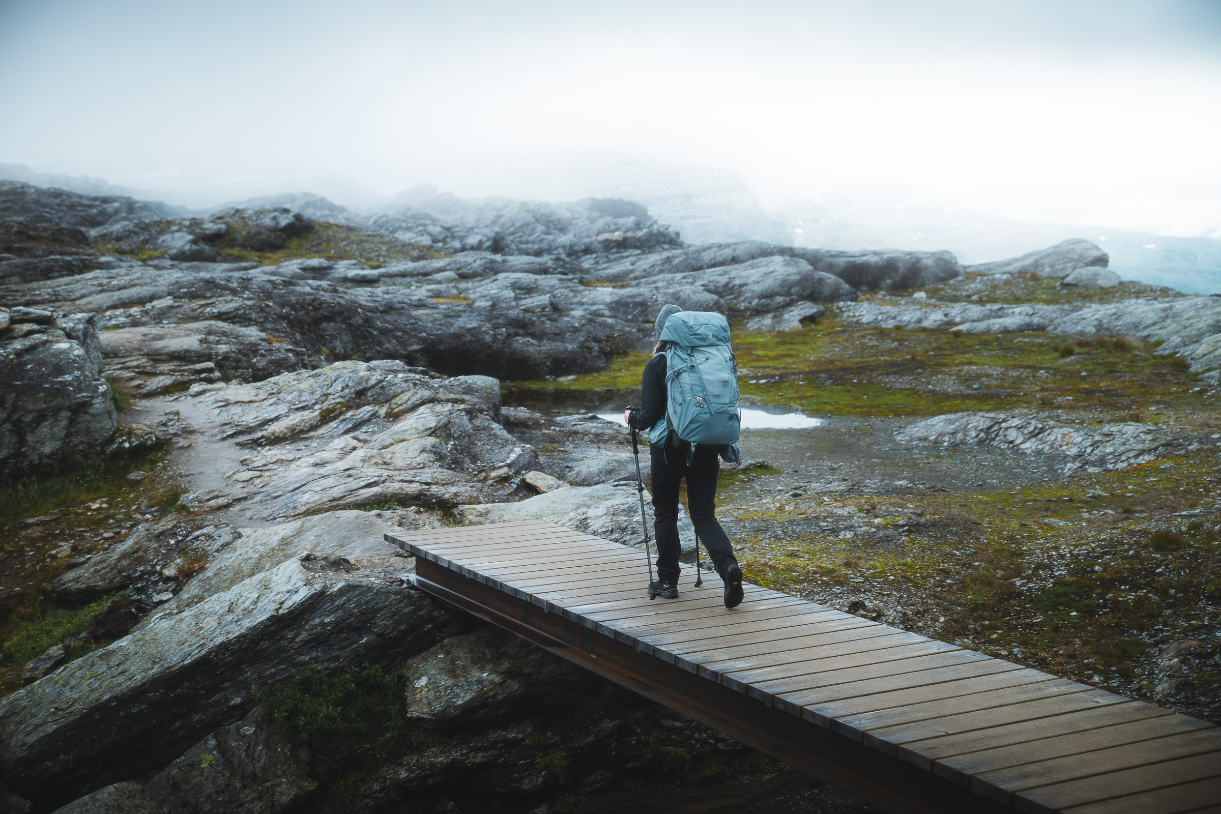 Backpacker crossing a wooden footbridge on a rocky plateau