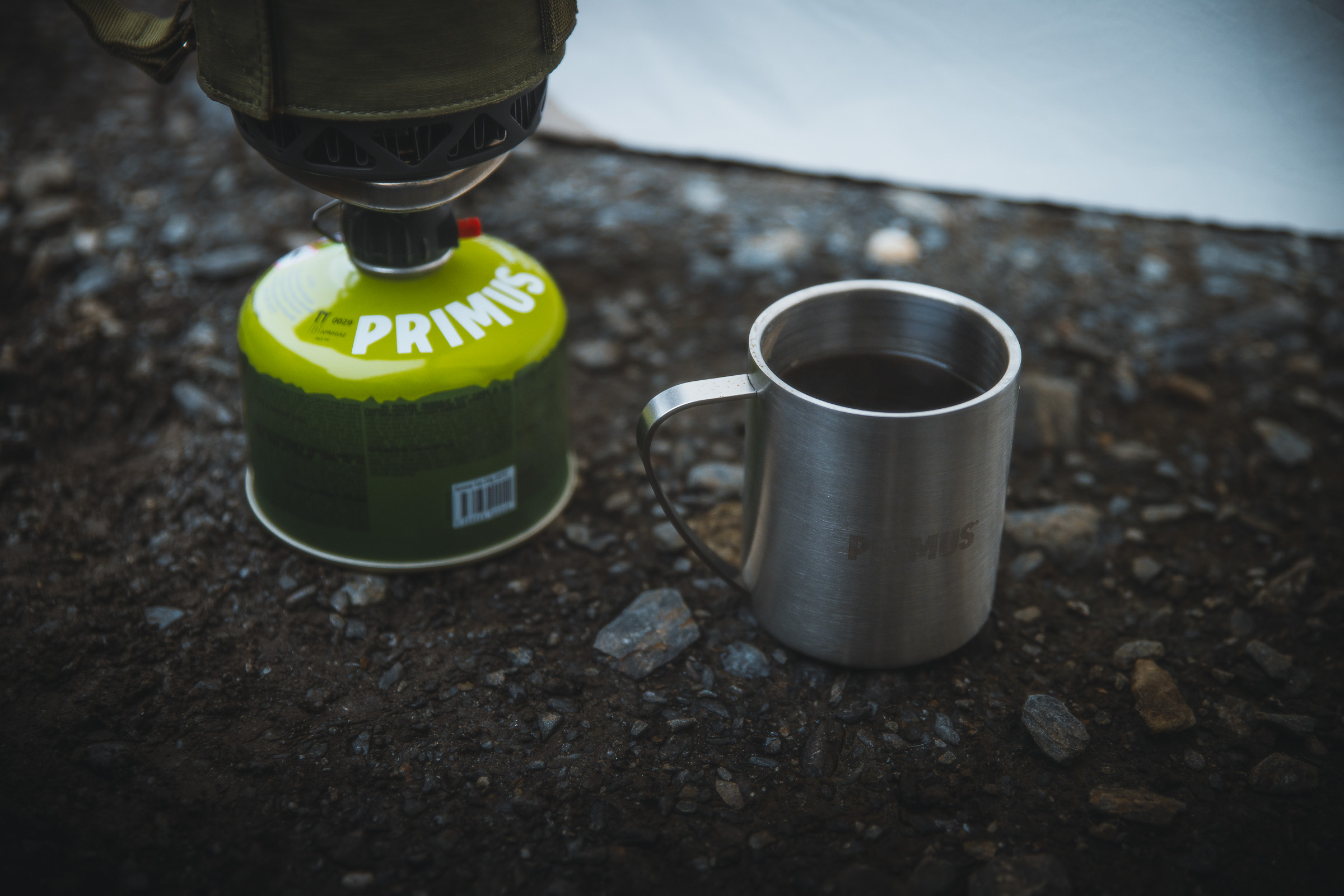 Camping stove and metal cup on wet ground